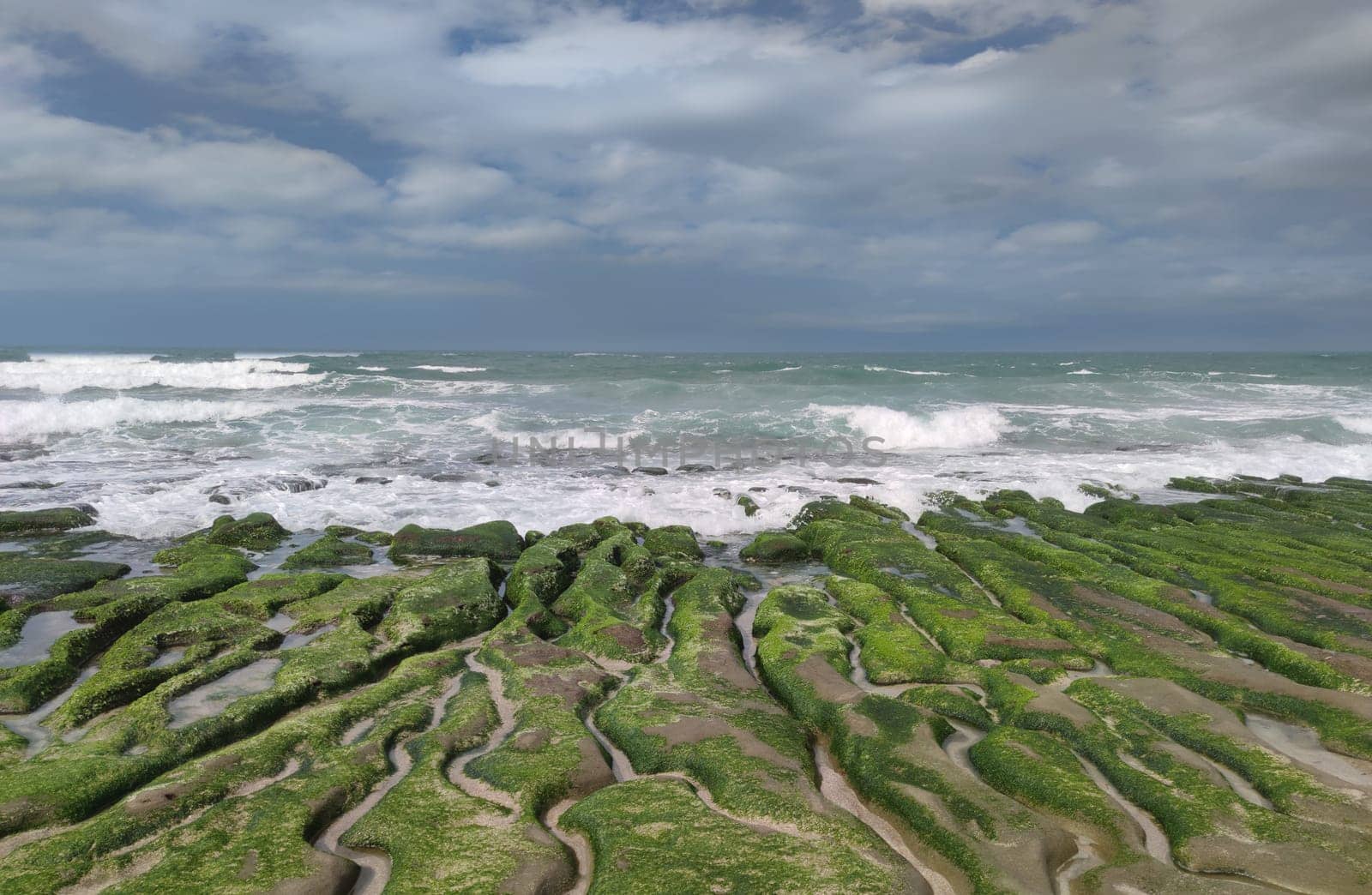 The Laomei Green Stone Trough is located in Shimen District on the North Coast, Every April and May, because the northeast monsoon slowly weakens, the local rock trough scientific name: tidal trench and sea erosion trench is covered with a large green seaweed