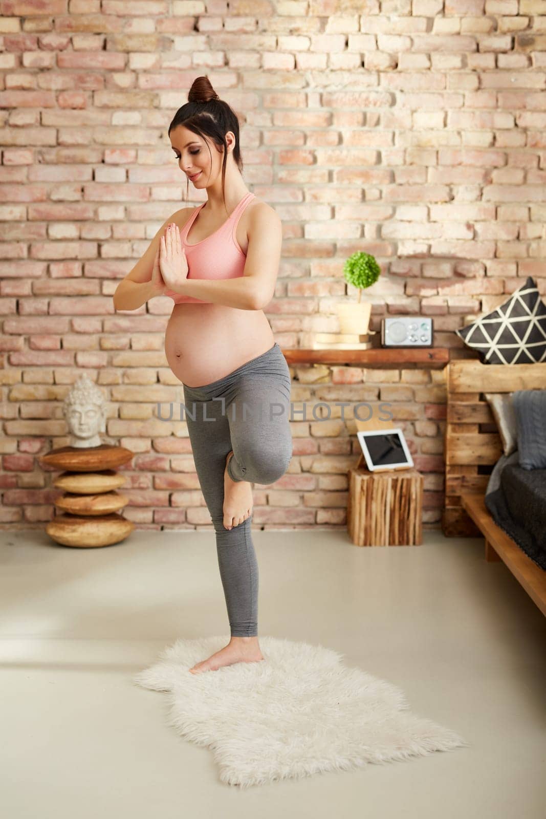 Pregnant woman doing yoga exercise at home standing.