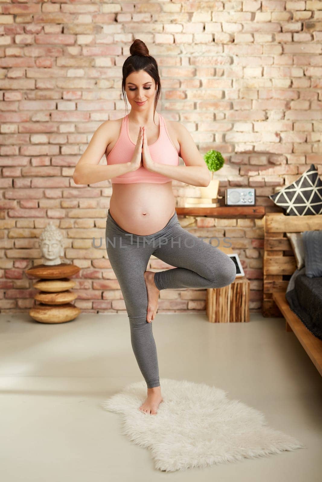 Pregnant woman doing yoga exercise at home standing.