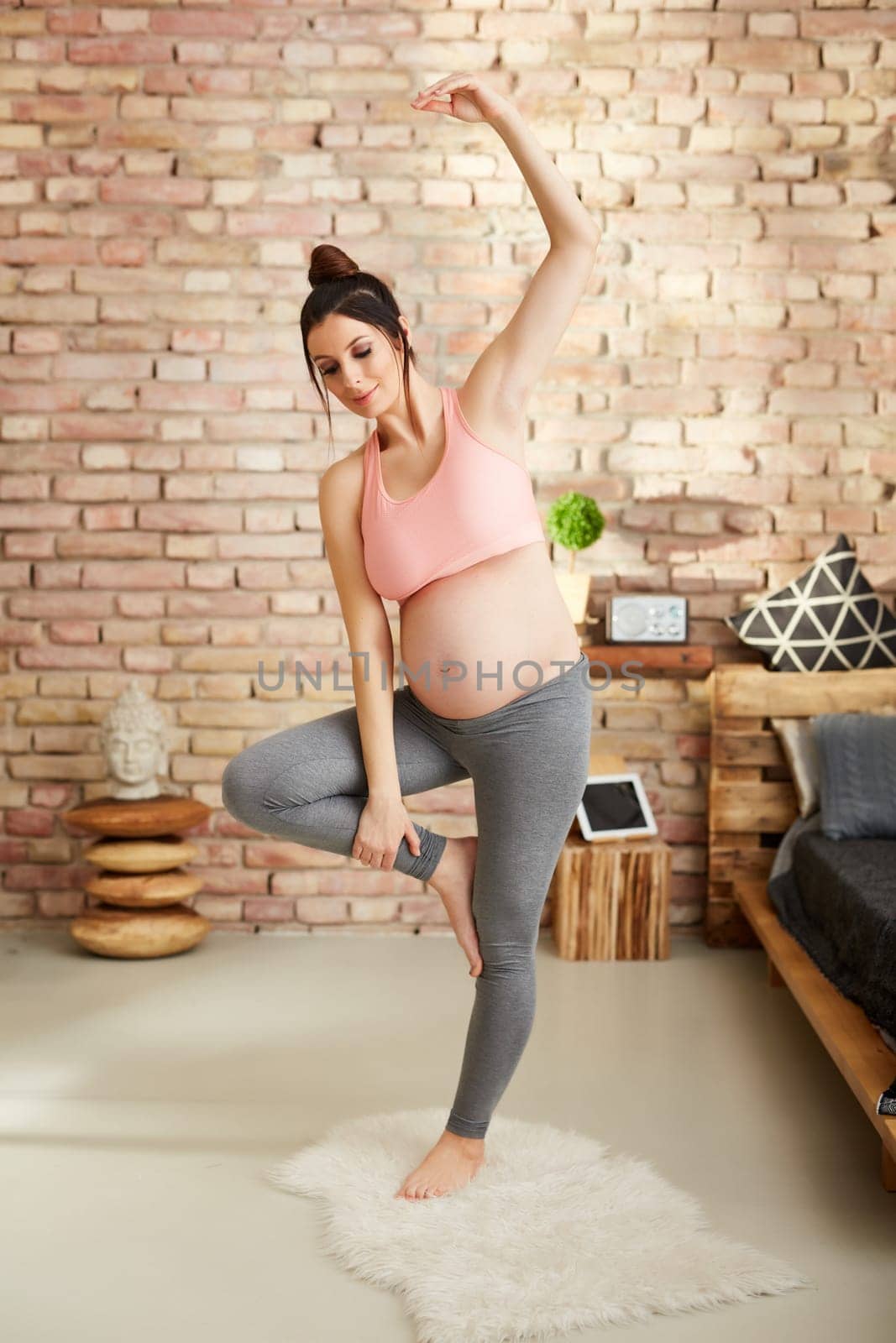 Pregnant woman doing yoga exercise at home standing.