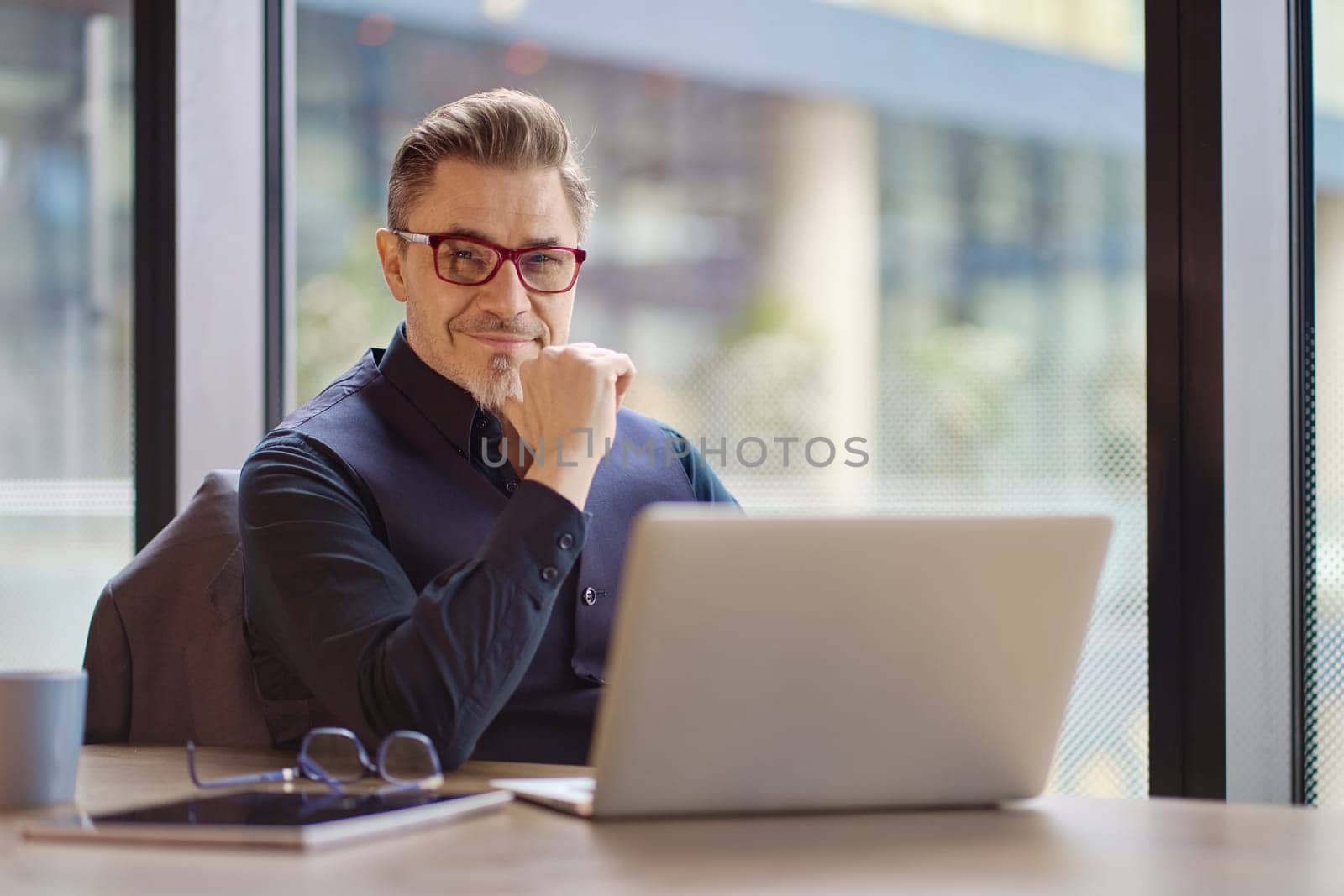 Business portrait - businessman using laptop computer in office. Happy middle aged man, entrepreneur working online.