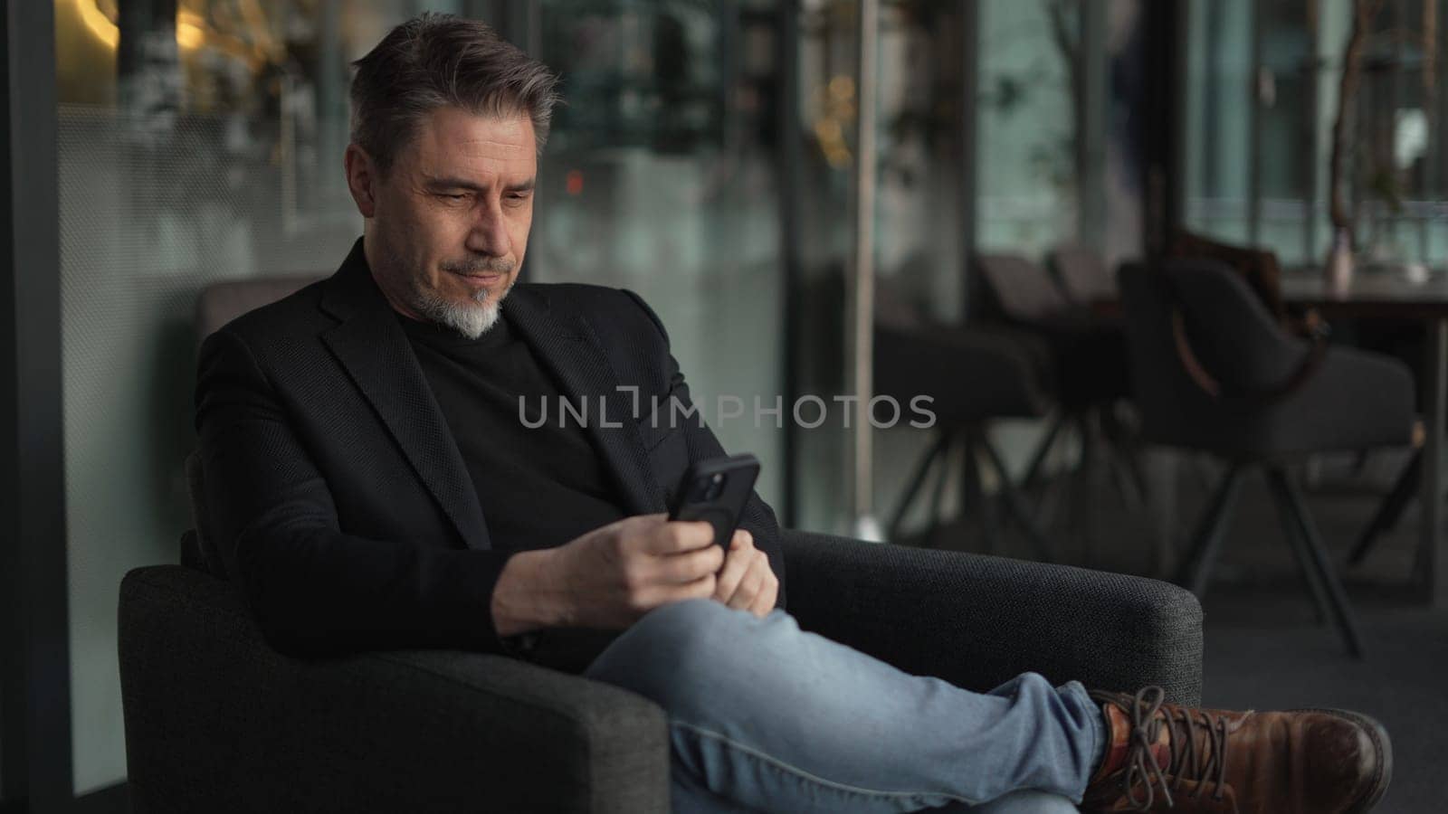 Businessman using phone in office. Serious middle aged man in business casual, Entrepreneur working online, reading finance report, thinking. .