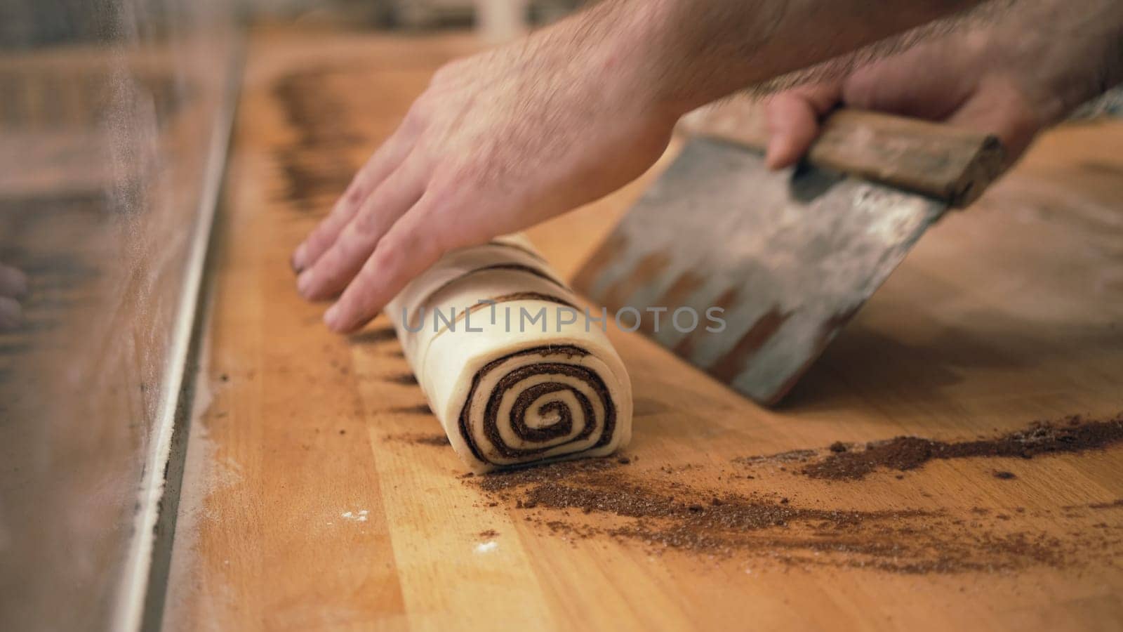 Baker working with handmade pastries in small bakery. Cocoa snail roll, chocolate roll. Closeup photo of not staged, authentic moment.