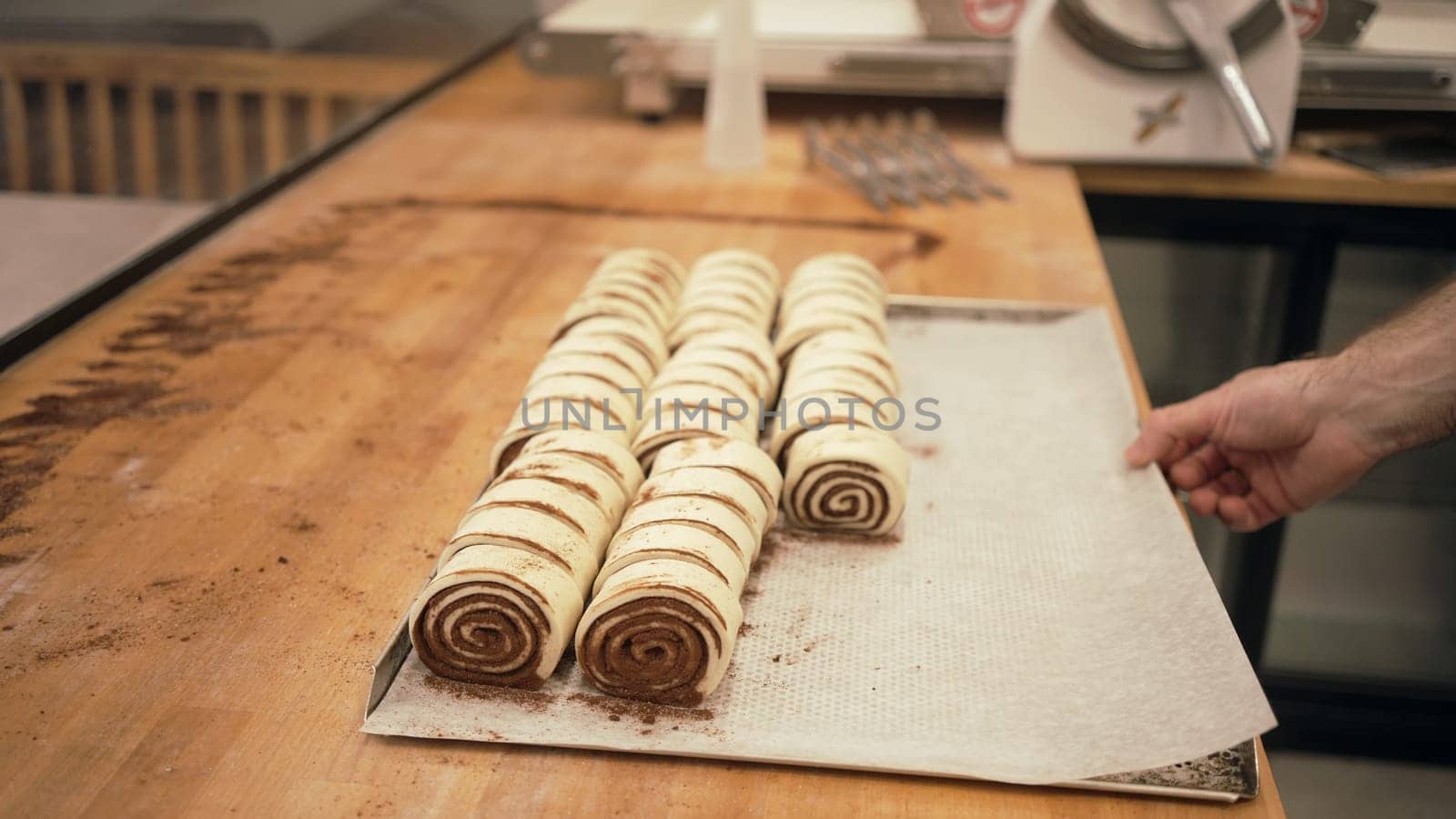 Baker working with handmade pastries in small bakery. Cocoa snail roll, chocolate roll. Closeup photo of not staged, authentic moment.
