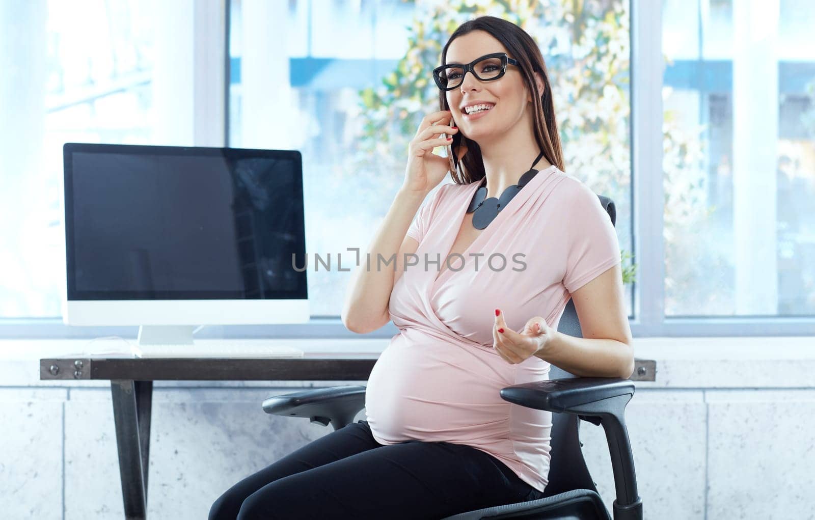 Today women working during pregnancy - happy pregnant woman working in modern business office.