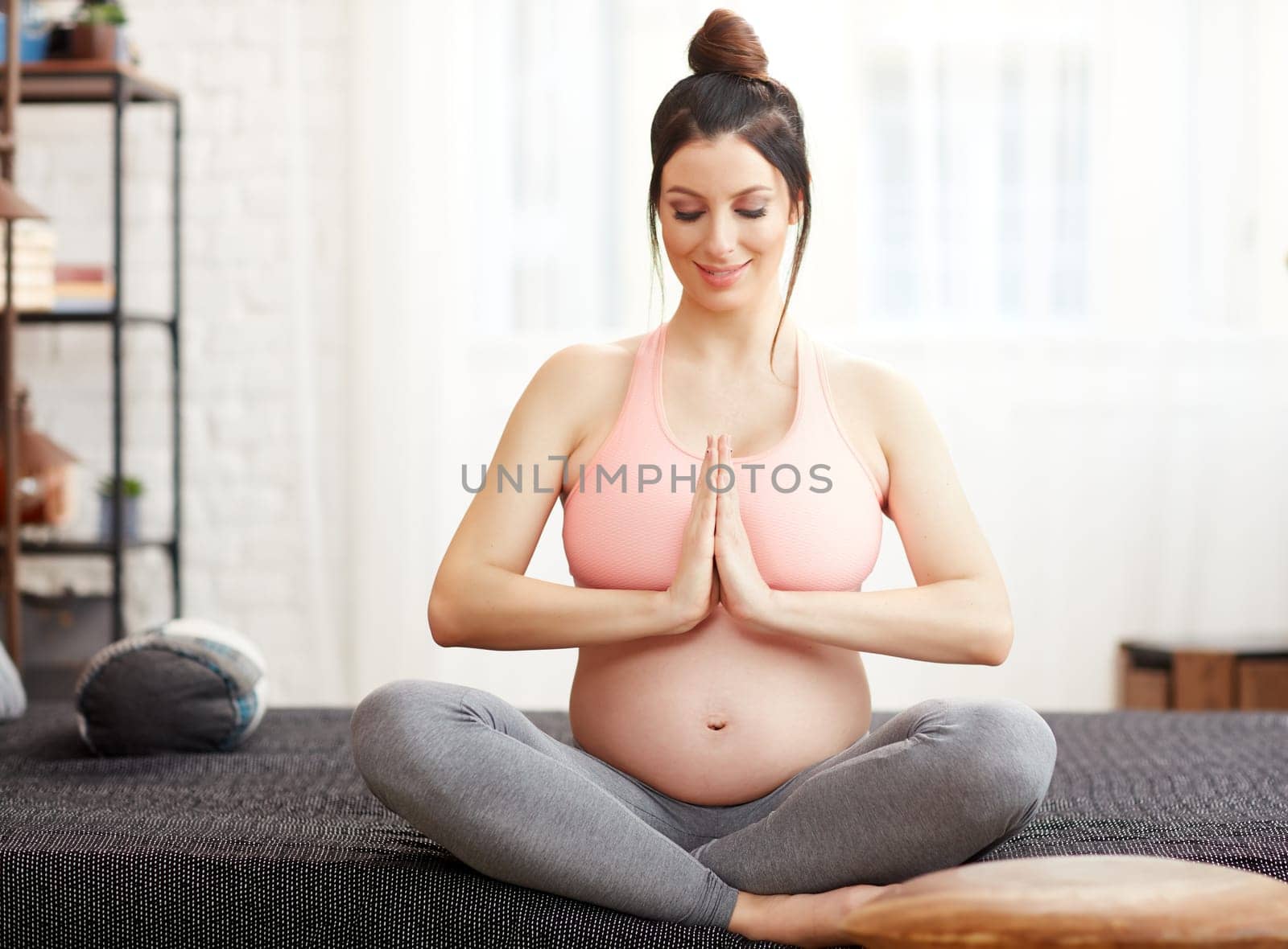 Pregnant woman doing yoga exercise at home relaxing with meditation.