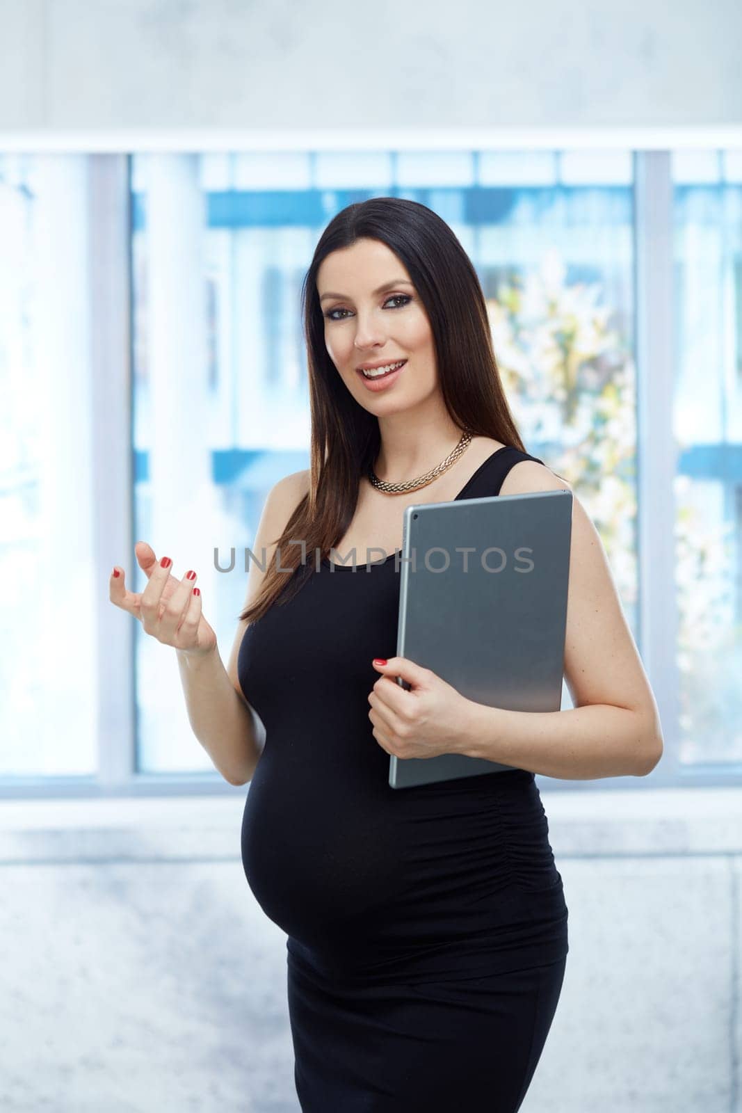 Portrait of pregnant businesswoman - Happy pregnant woman in business dress working in office, holding tablet.
