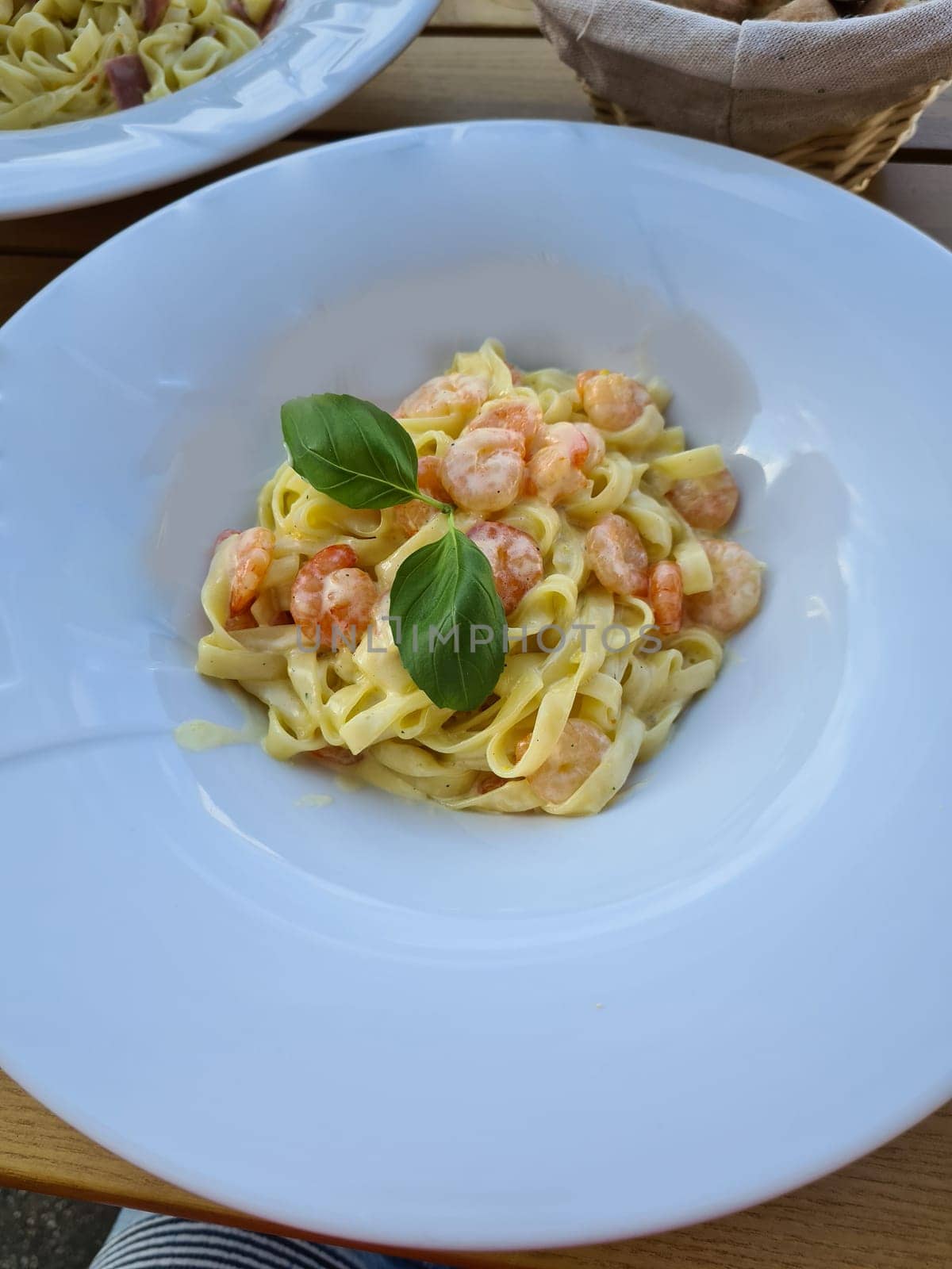 Plate of delicious pasta with shrimps on white wooden table, top view