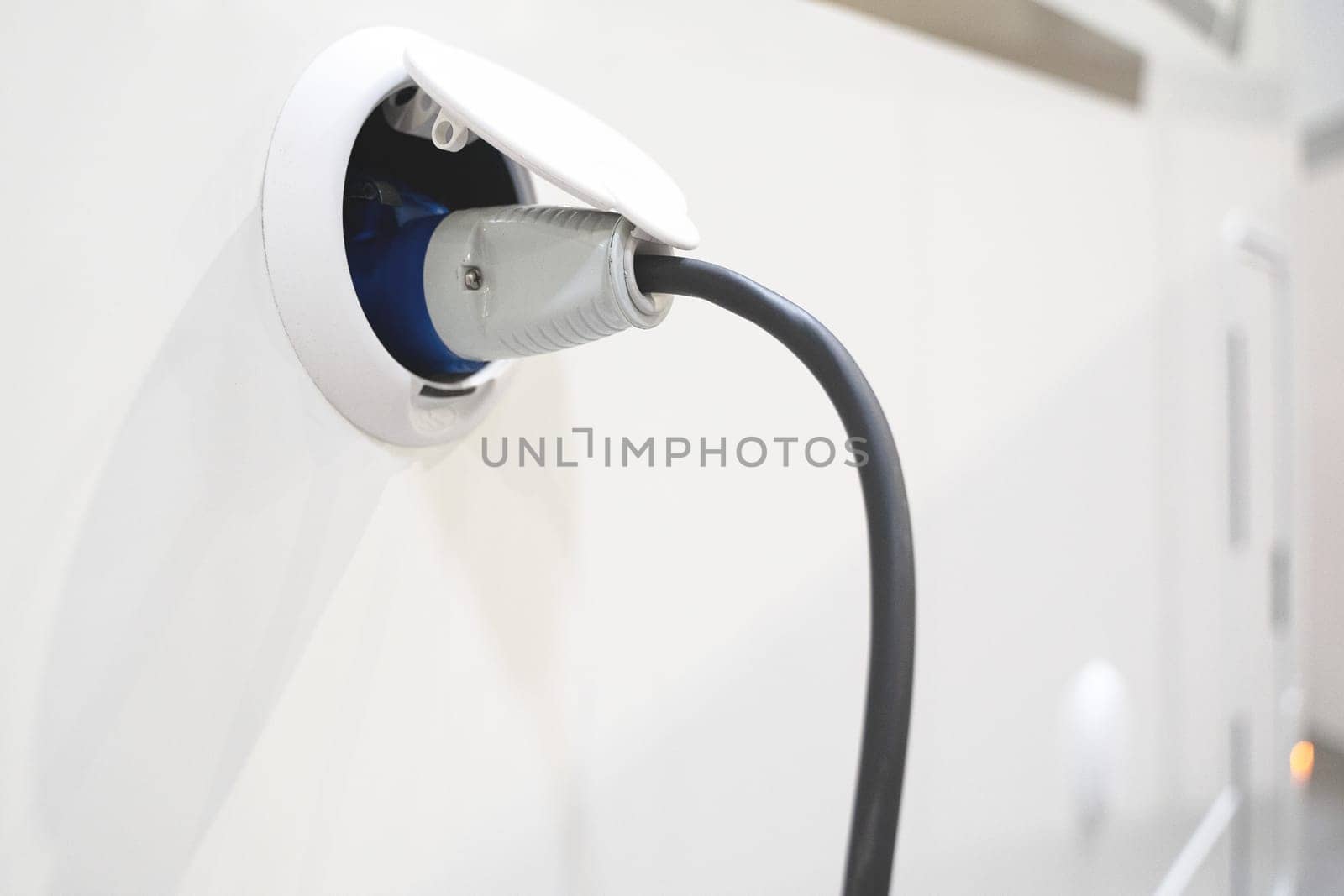perspective view closeup of motorhome electricity outlet plug attached to stationary white RV travel campervan