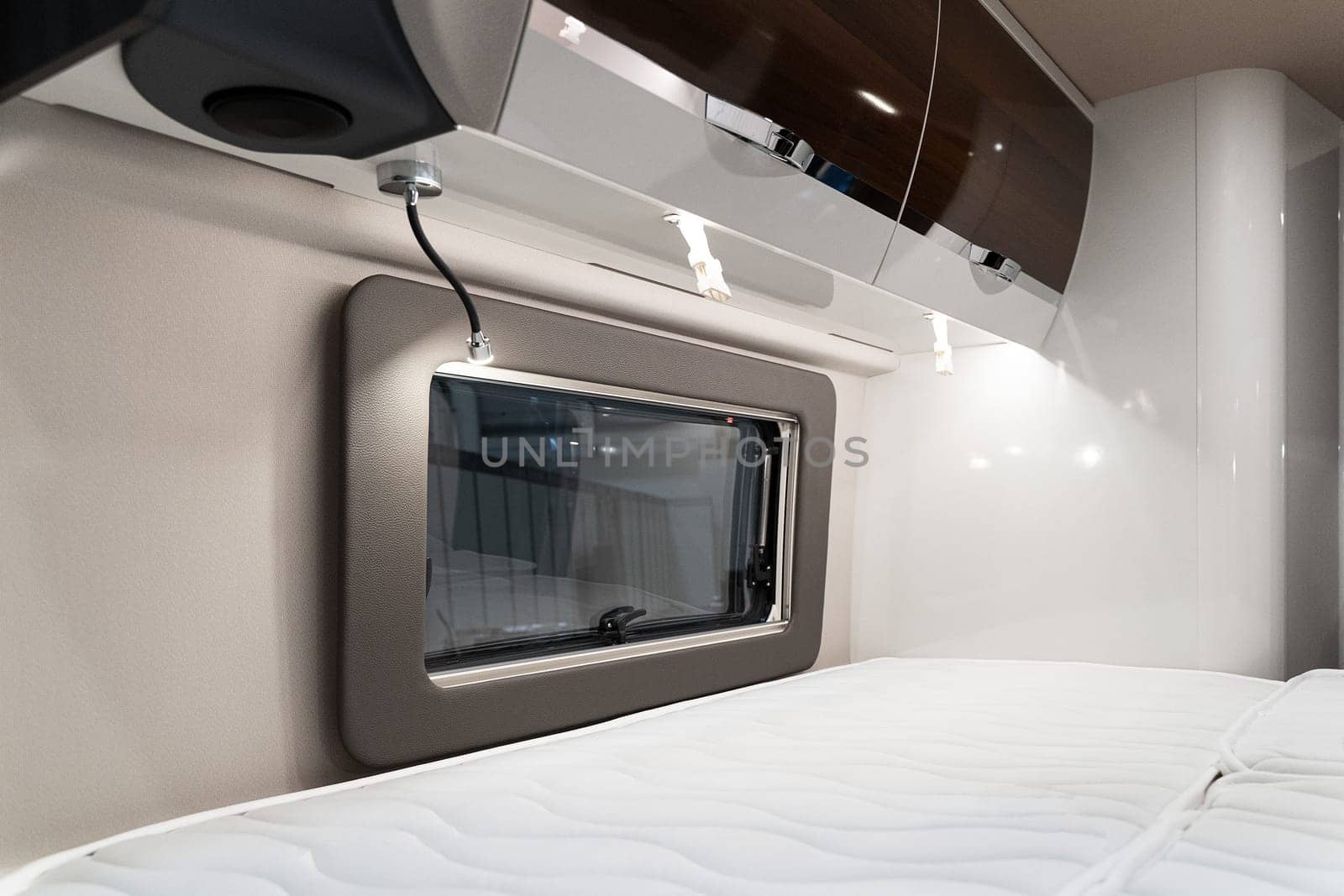 closeup of bed near window and storage shelves inside empty bedroom in luxury RV camper trailer interior