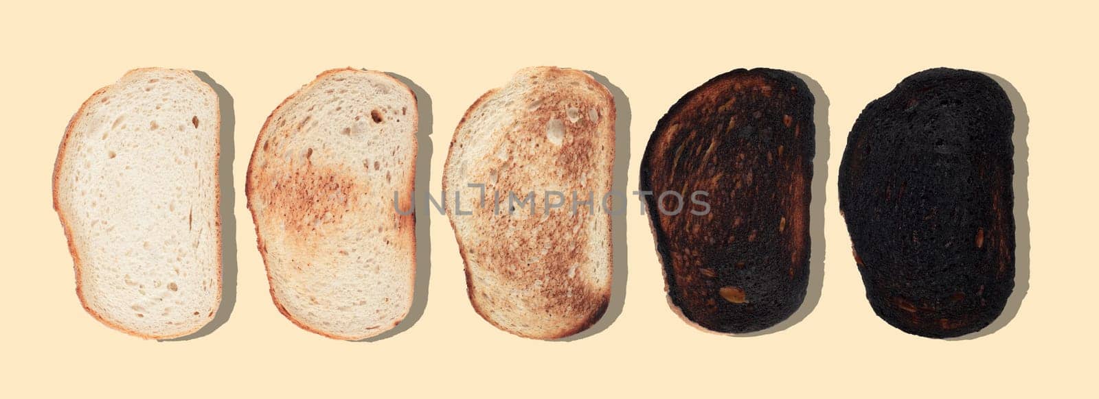 top view of slices of bread at different stages of toasting with last one completely charred and burnt on brown background