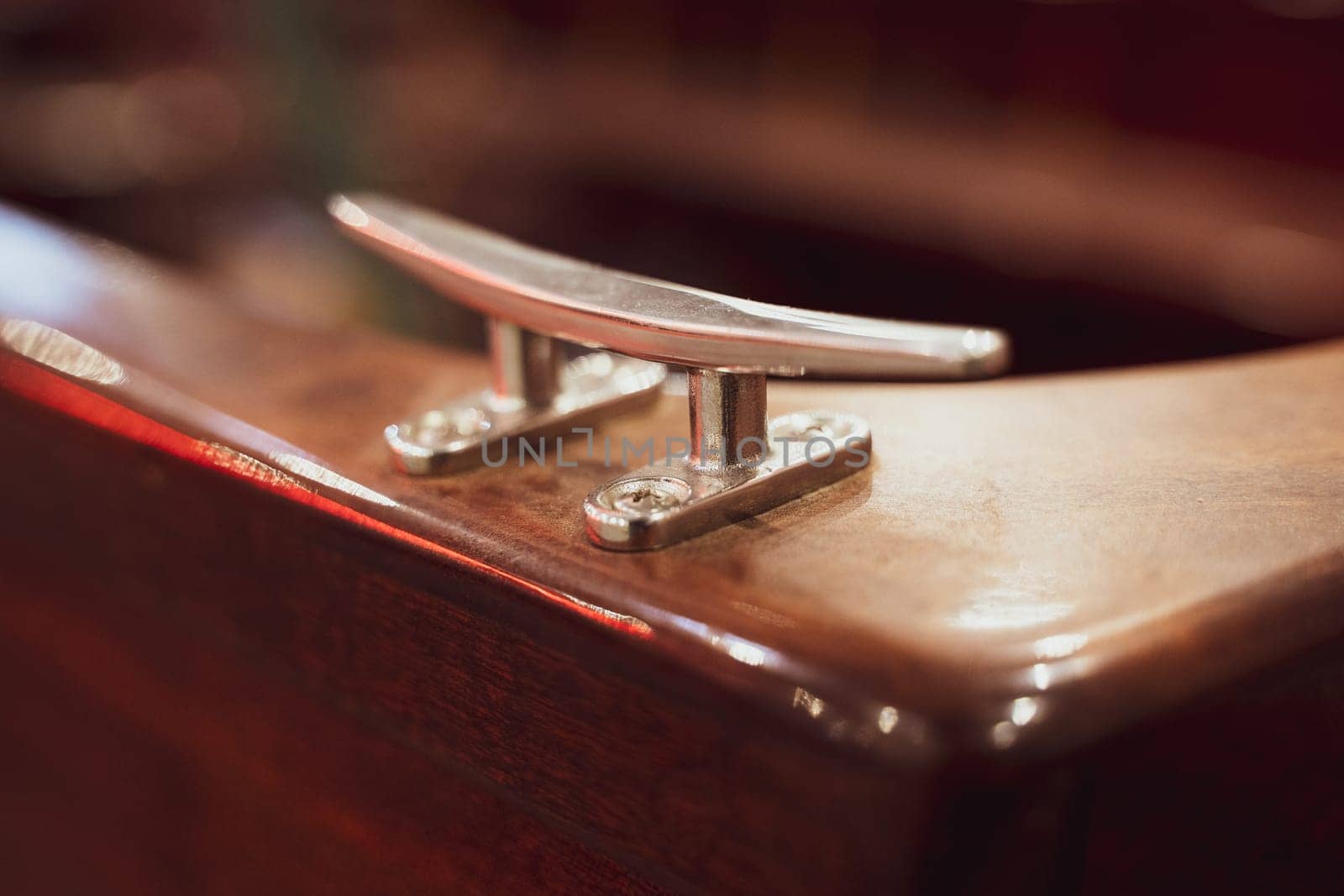 closeup with selective focus on piece of marine cleat equipment on brown wooden boat yacht
