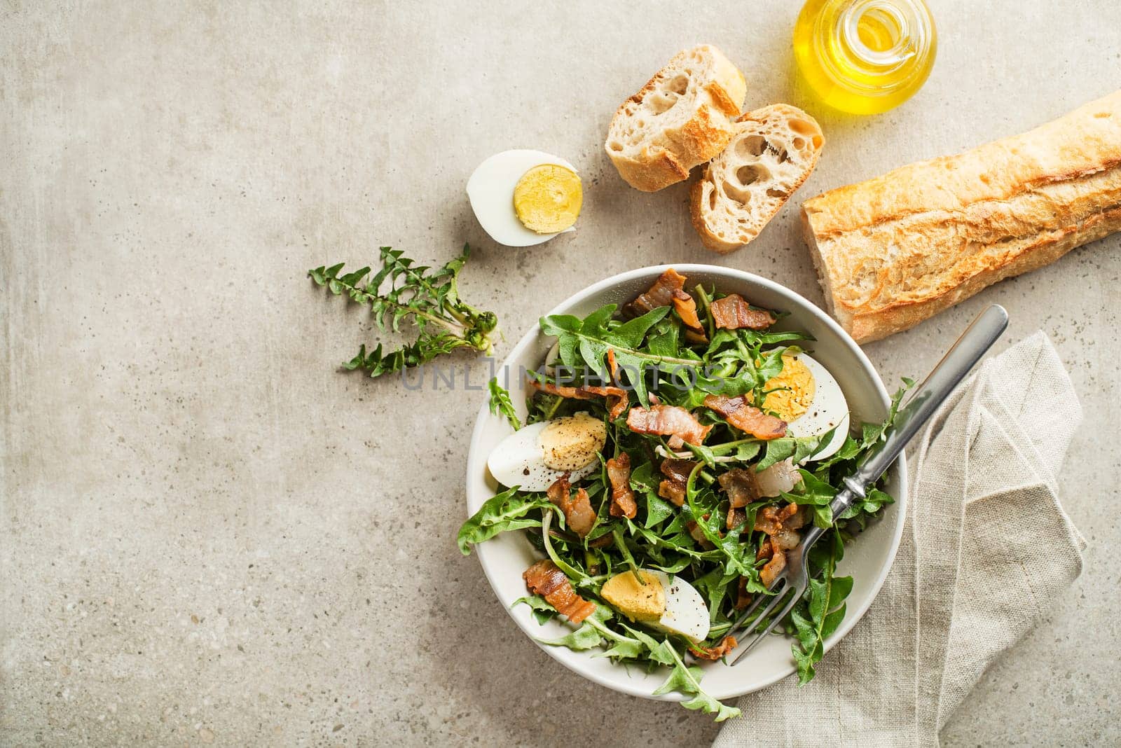 Dandelion salad with egg and bacon on grey background