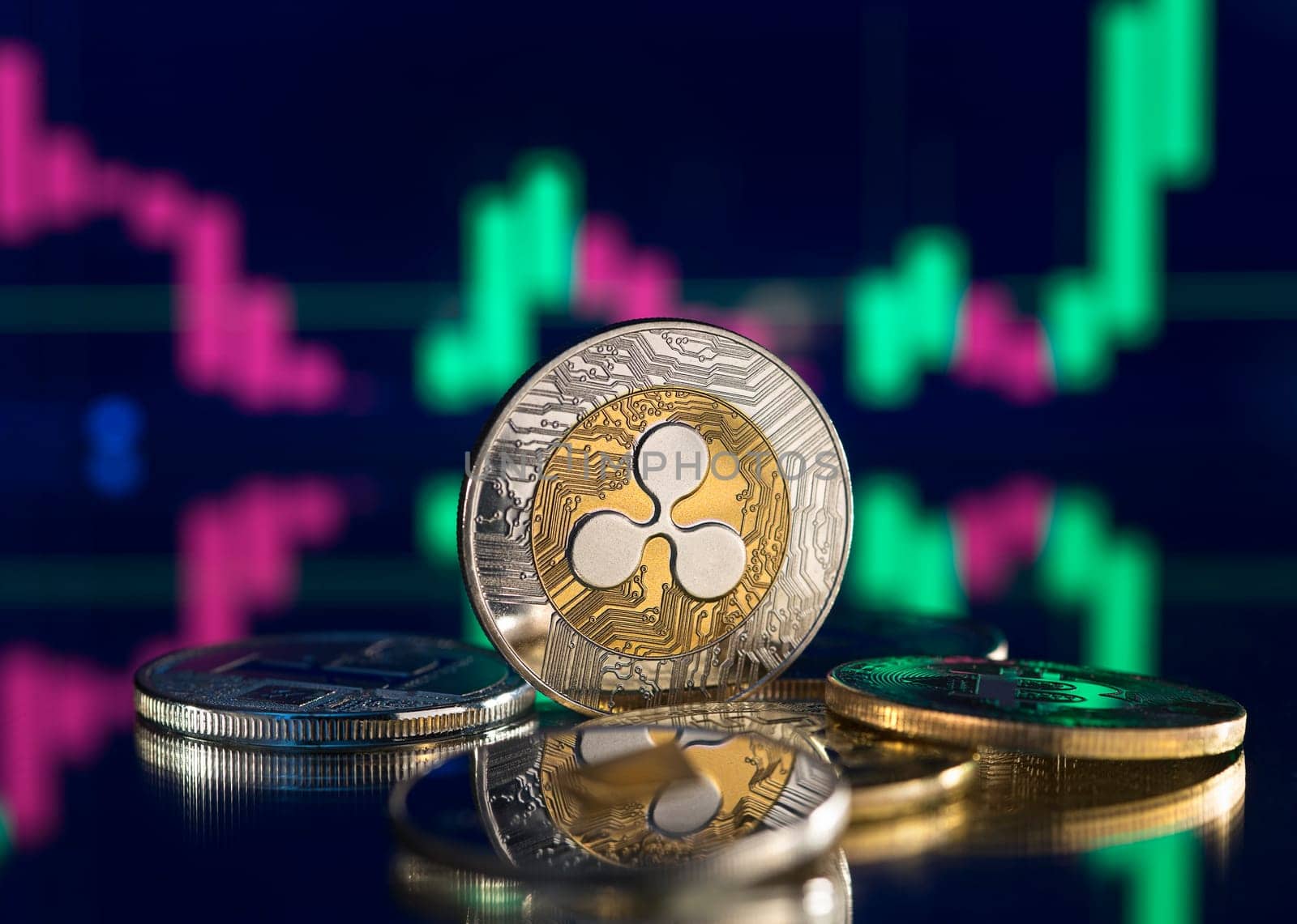 Bitcoin and cryptocurrency investing concept. Cryptocurrency golden coin with gold ripple symbol. Rise and fall charts of alt coins.
