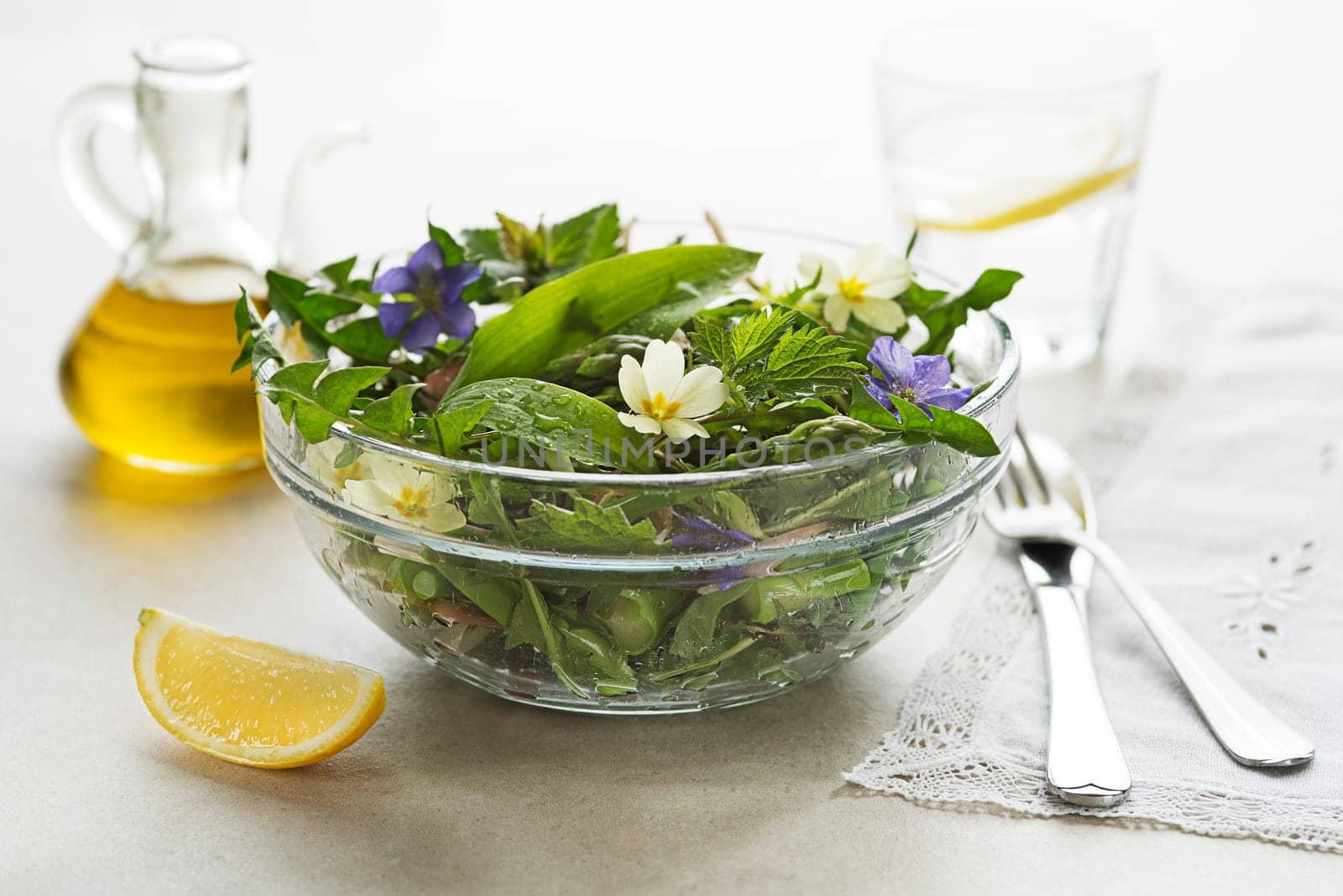 Spring salad with dandelion, asparagus, wild garlic, flowers, nettle and dressing sauce. Healthy spring detox food ingredients.