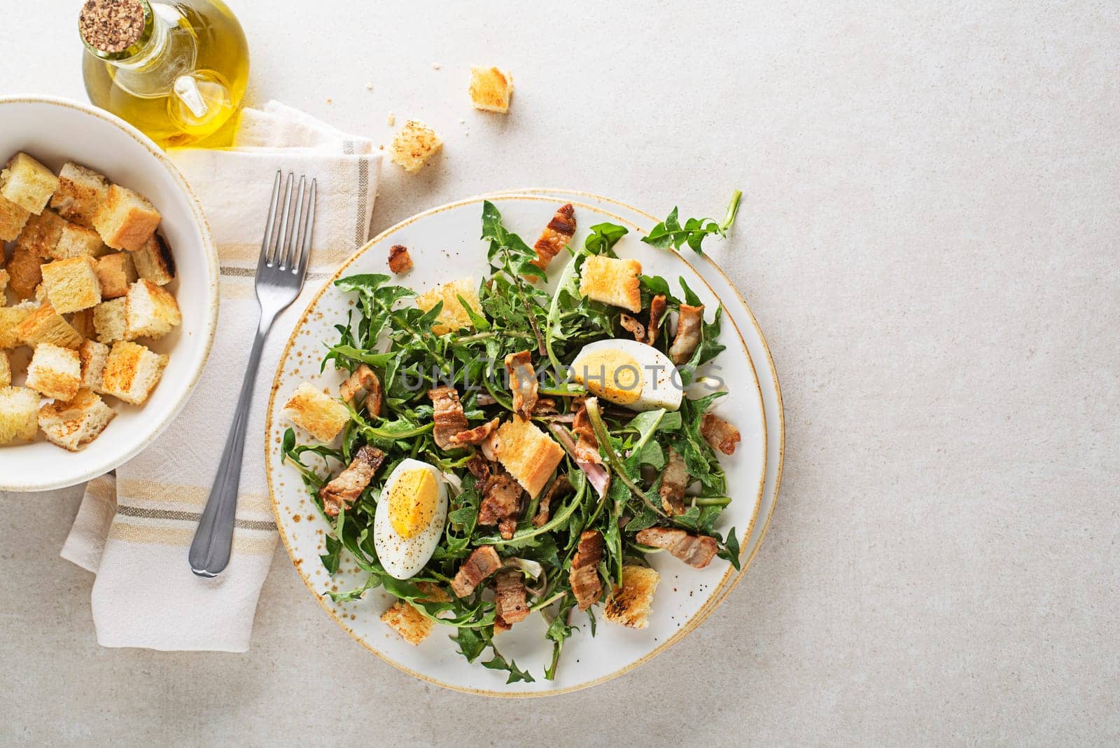 Dandelion salad with egg bacon and croutons on grey background