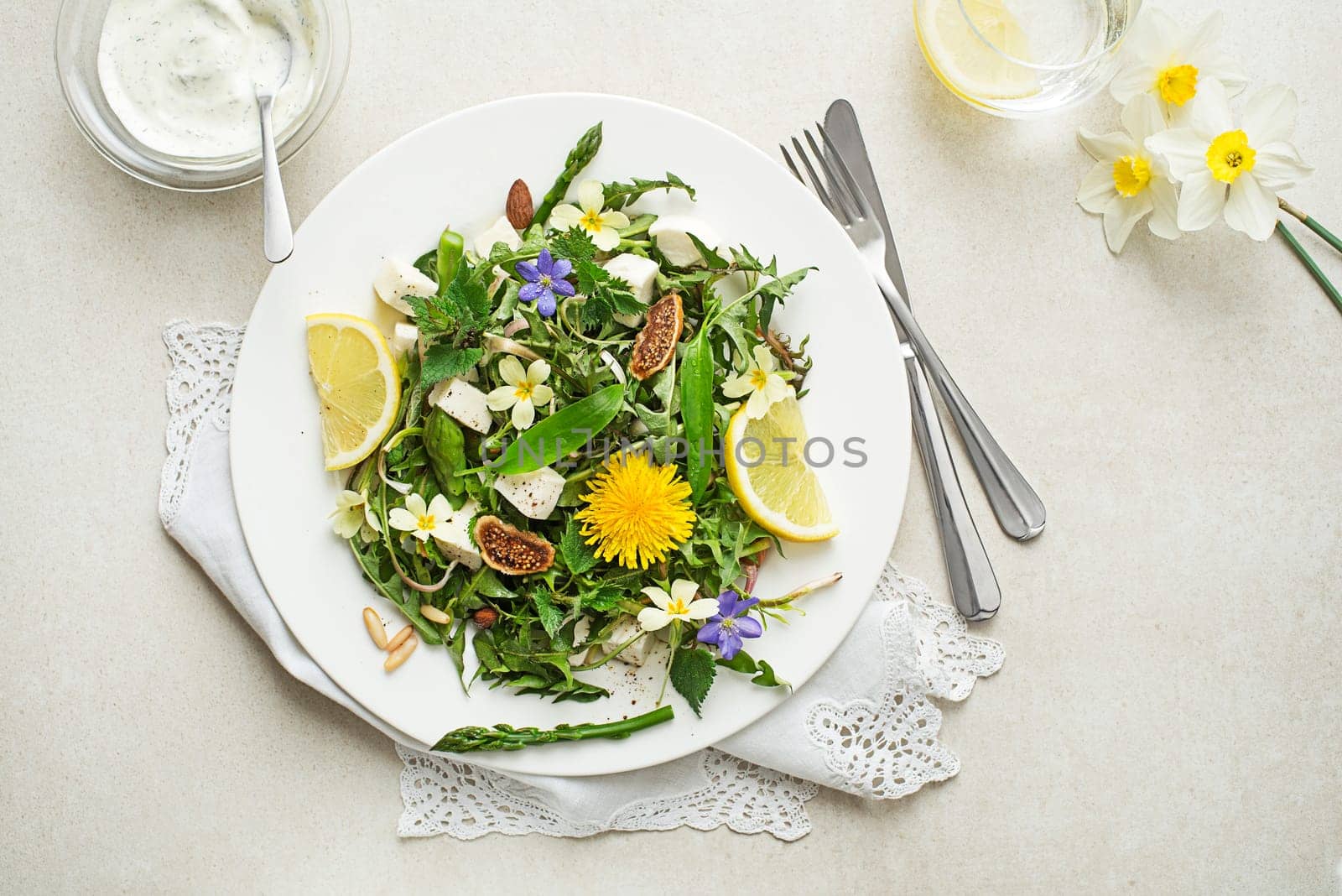Spring salad with dandelion, asparagus, wild garlic, flowers, nettle and cream cheese. Healthy spring detox food ingredients.