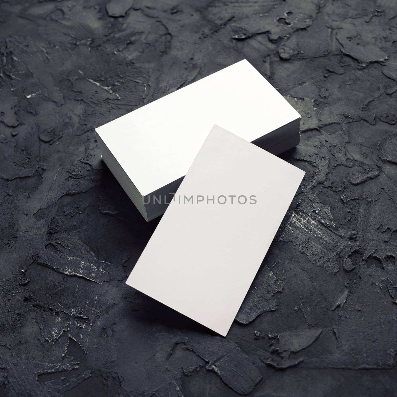 Blank white business cards on black plaster background. Mockup for branding identity. Template for graphic designers portfolios.