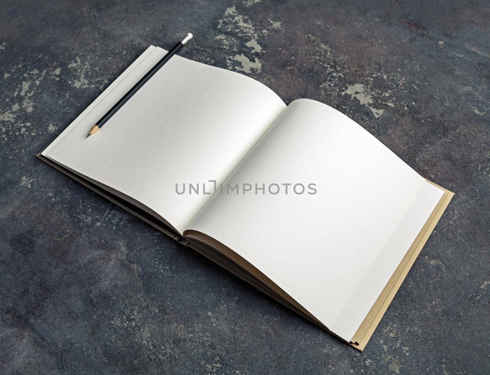 Photo of blank book and pencil on concrete background. Branding mock up.