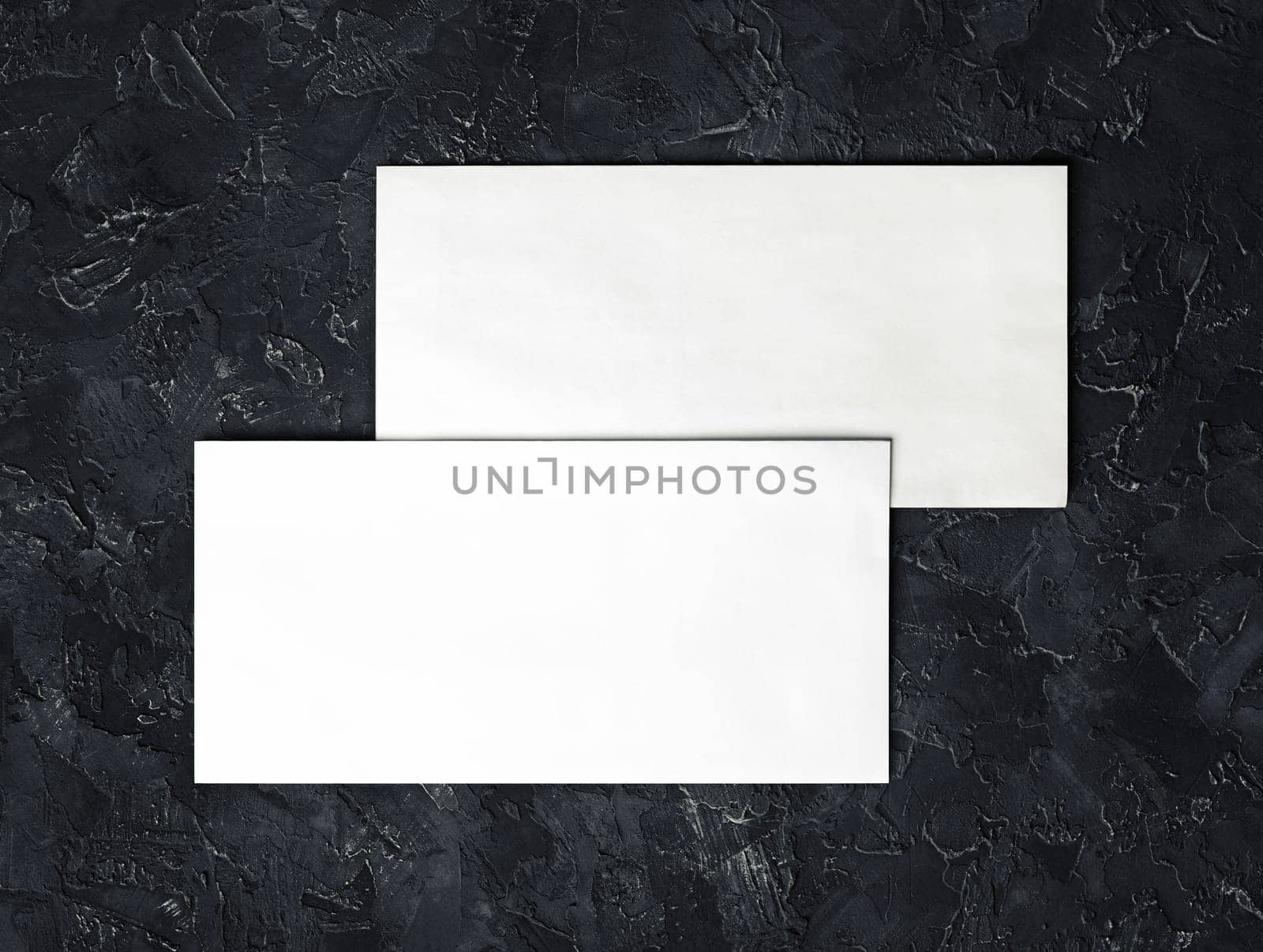 Two blank envelopes mockup on black plaster background. Template for branding identity. Top view.