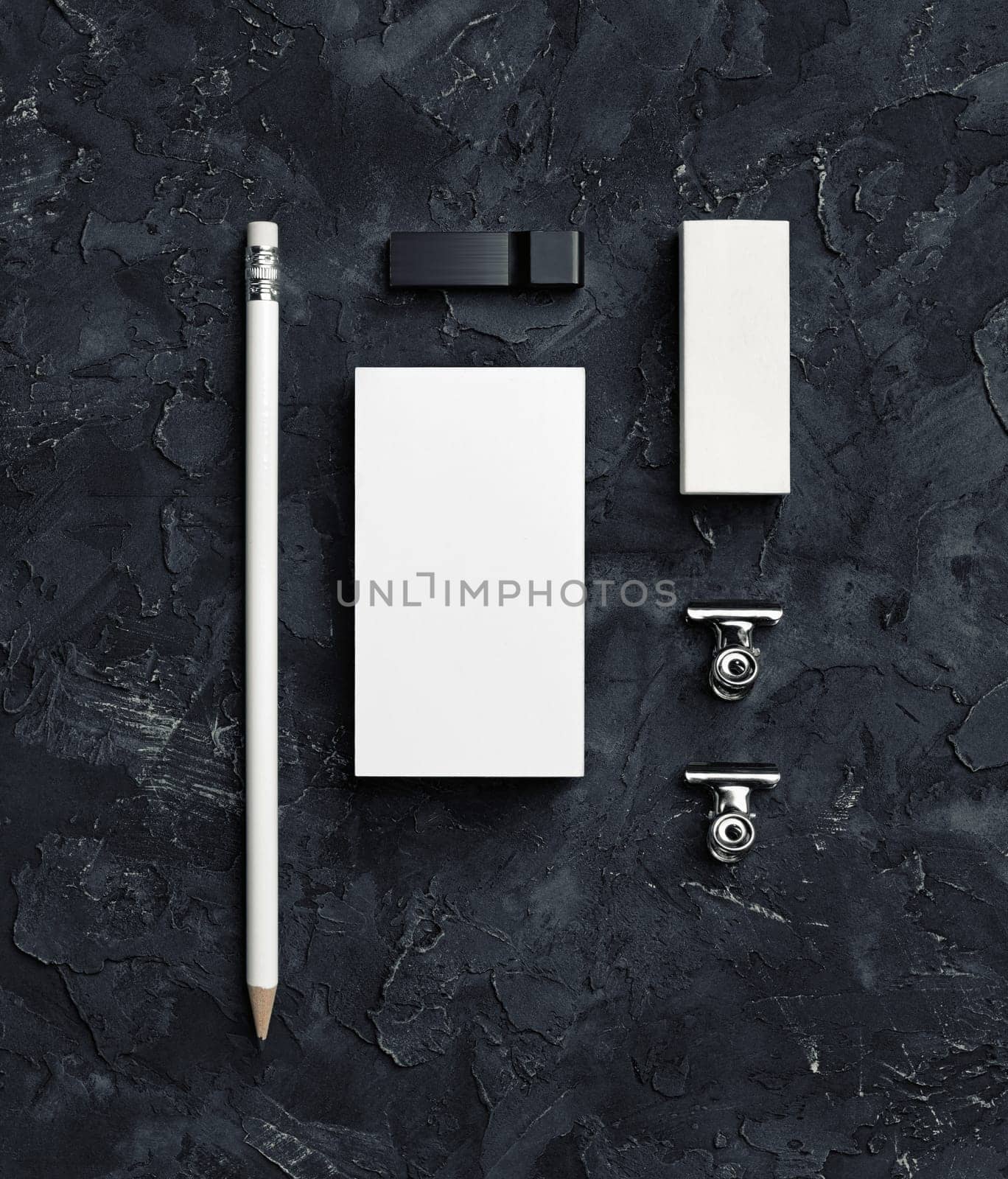 Corporate identity template on black plaster background. Blank business card, pencil, eraser, usb flash drive and metal clips. Top view.