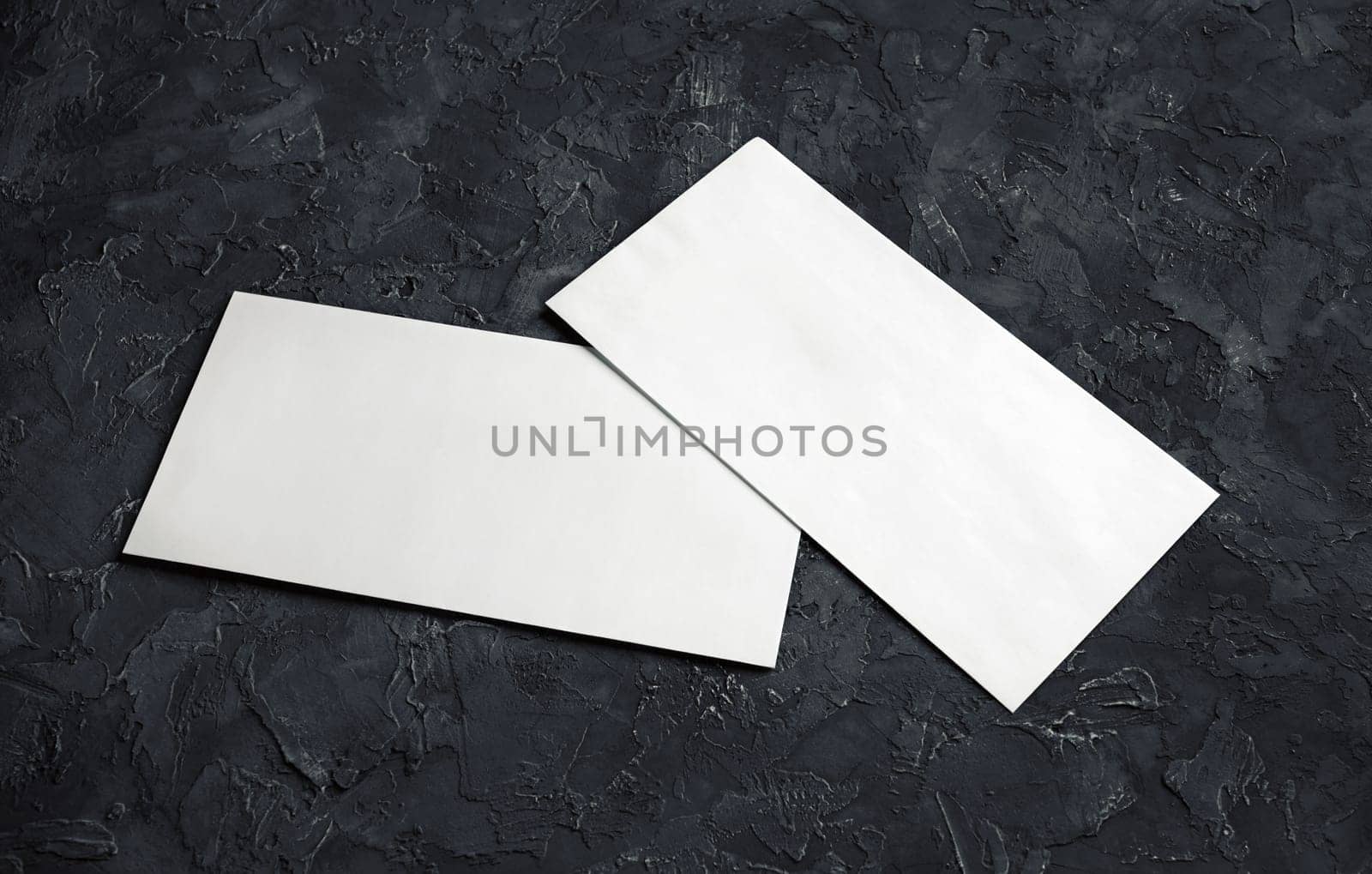 Blank white paper envelopes on black plaster background. Template for your design.