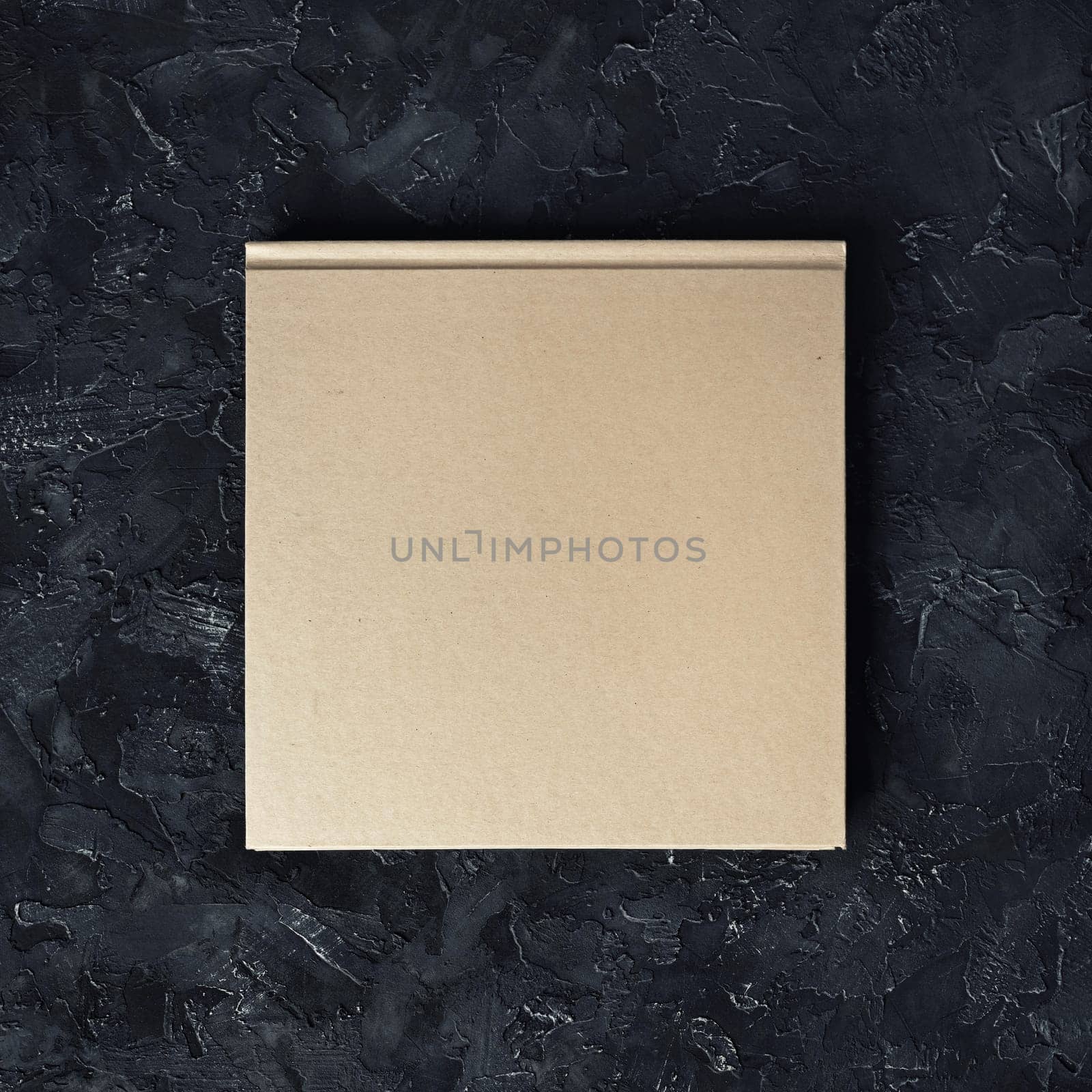 Closed blank square booklet on black plaster background. Top view.