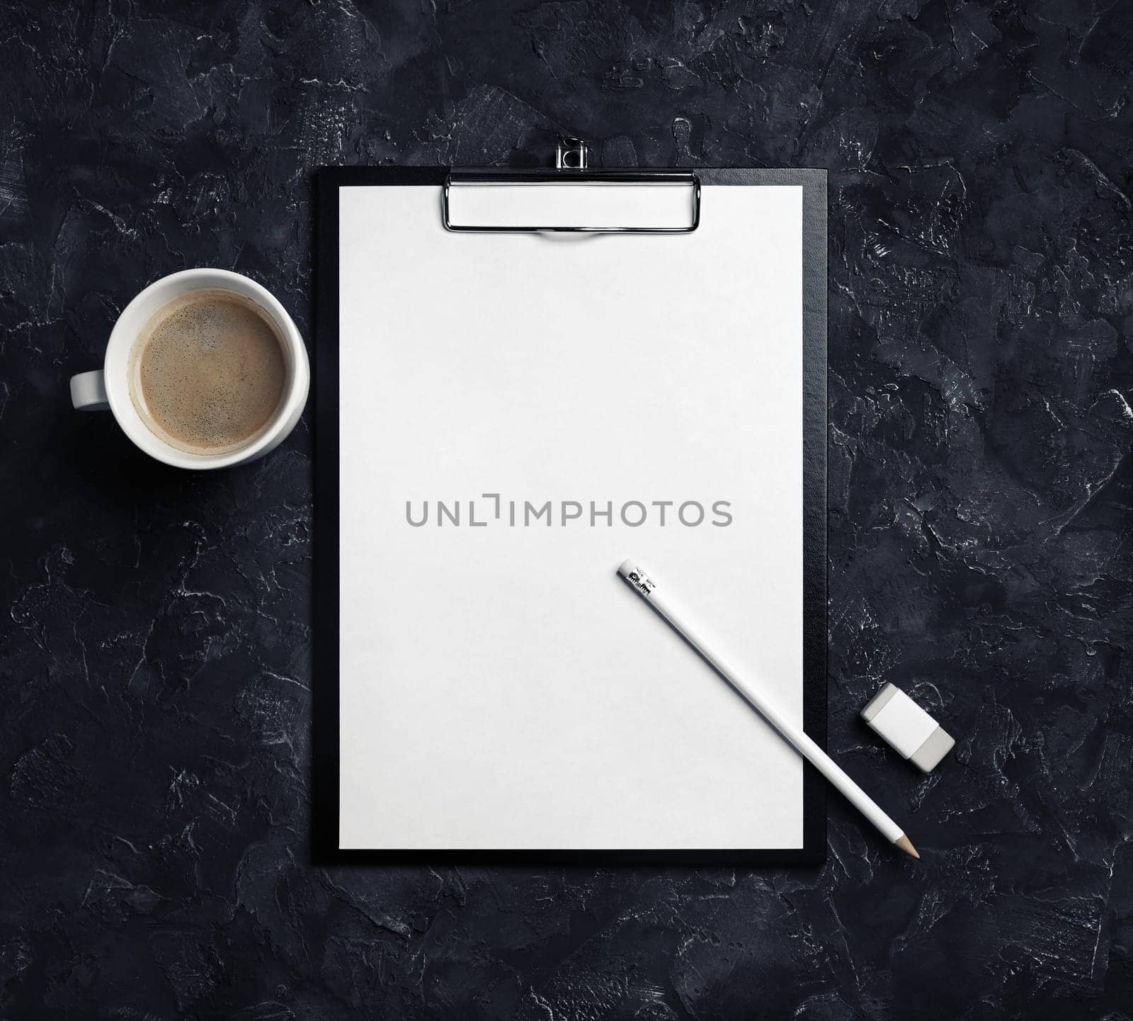 Clipboard with blank letterhead, coffee cup, pencil and eraser on black plaster background. Top view.