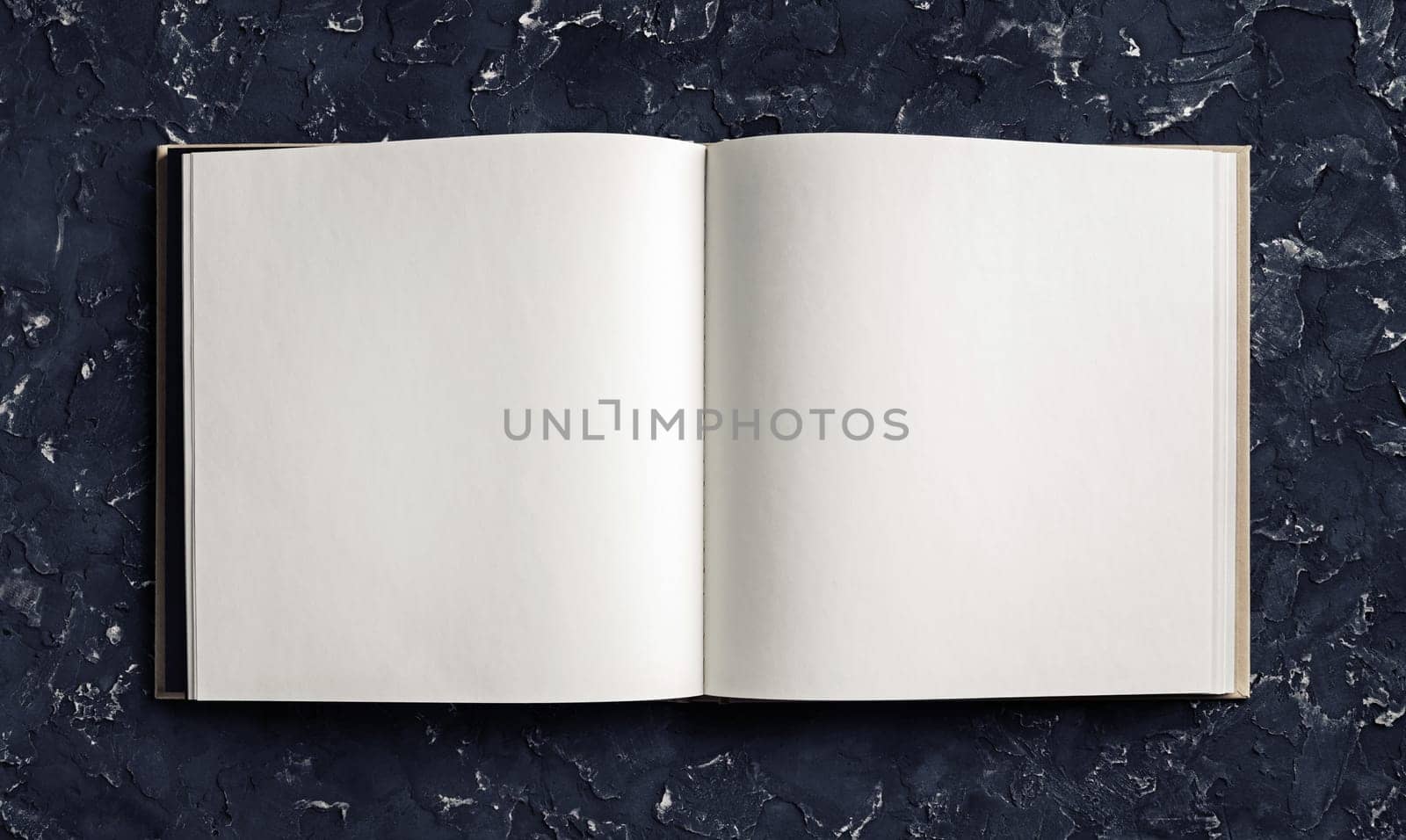 Blank opened booklet on black plaster background. Responsive design template. Top view. Flat lay.