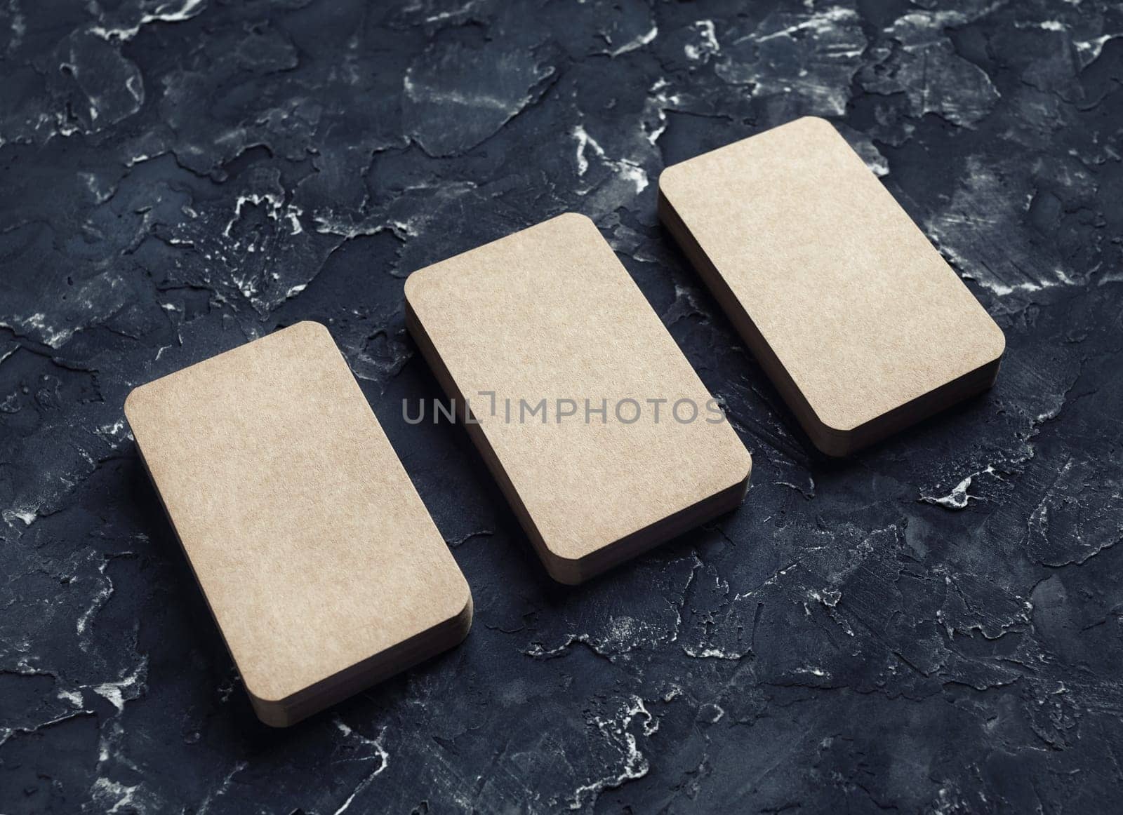 Blank kraft business cards on black plaster background. Mockup for branding identity. Template for graphic designers portfolios.