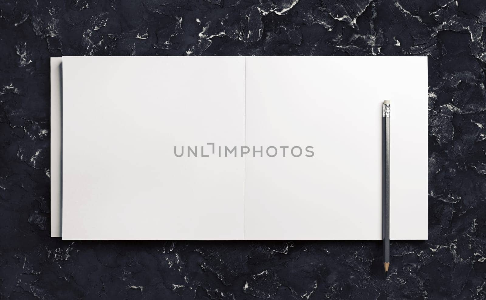 Blank brochure and pencil on black plaster background. Blank stationery template. Top view.