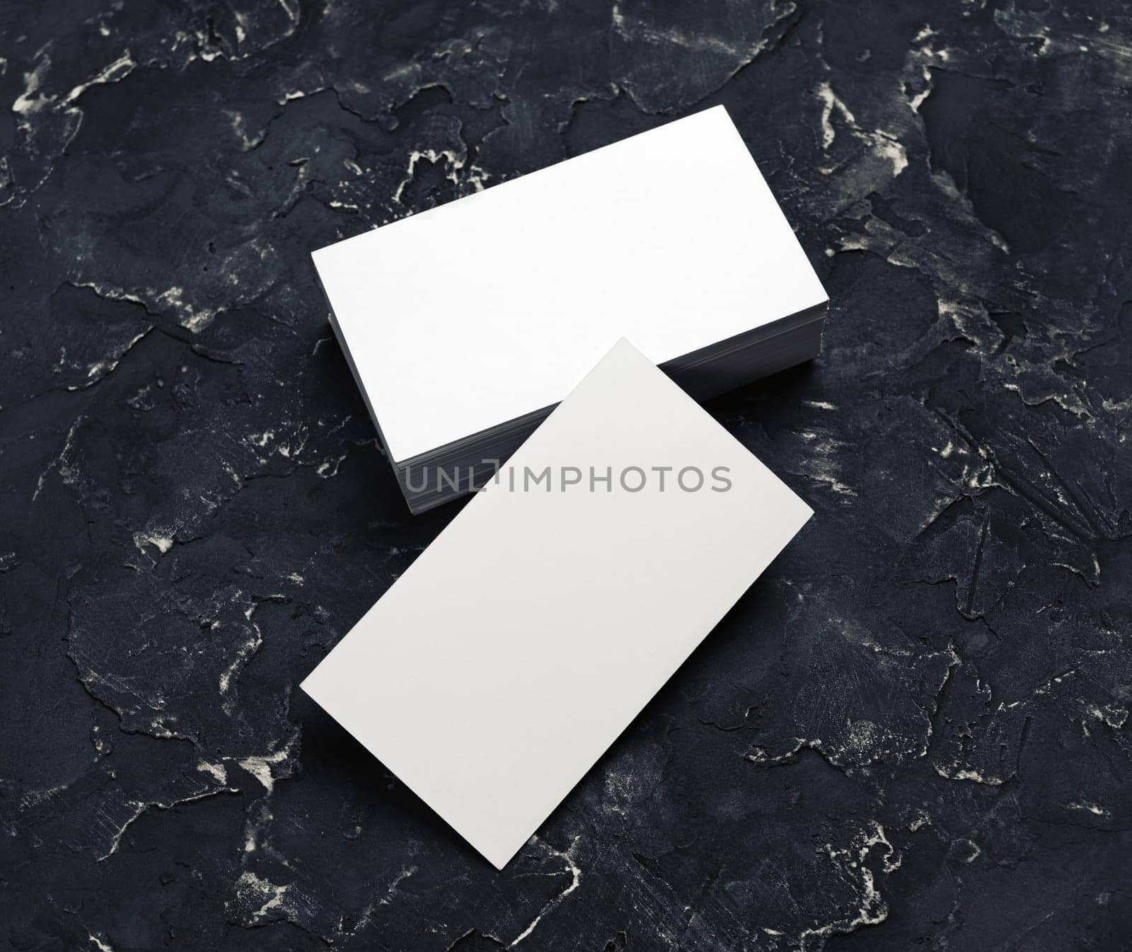 Blank business cards on black plaster background. Mock-up for branding identity.