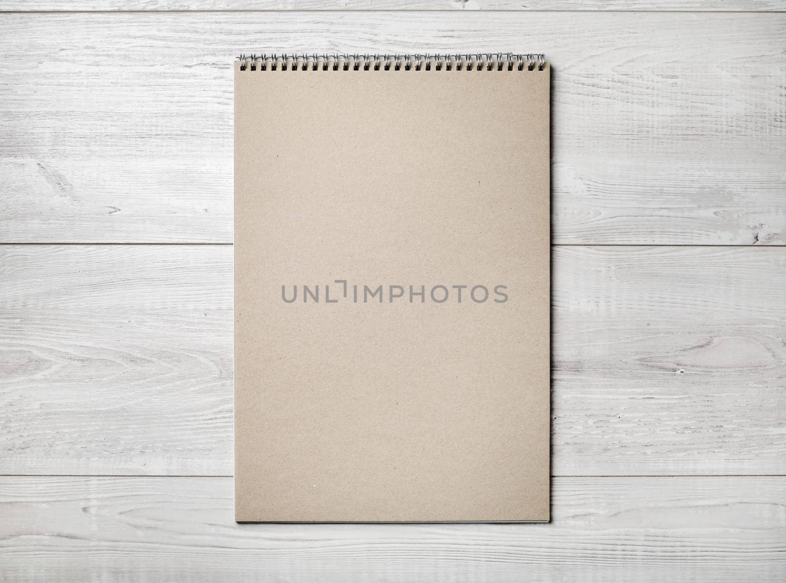 Photo of blank kraft sketchbook on light wooden background. Flat lay.