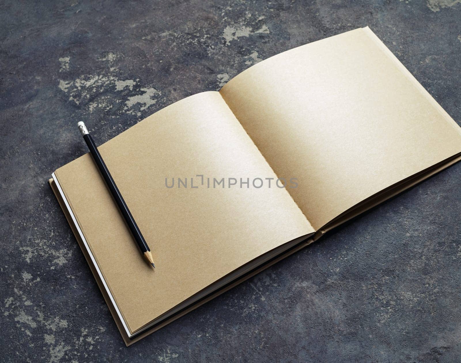 Open blank craft paper brochure and pencil on concrete background. Branding mock up.