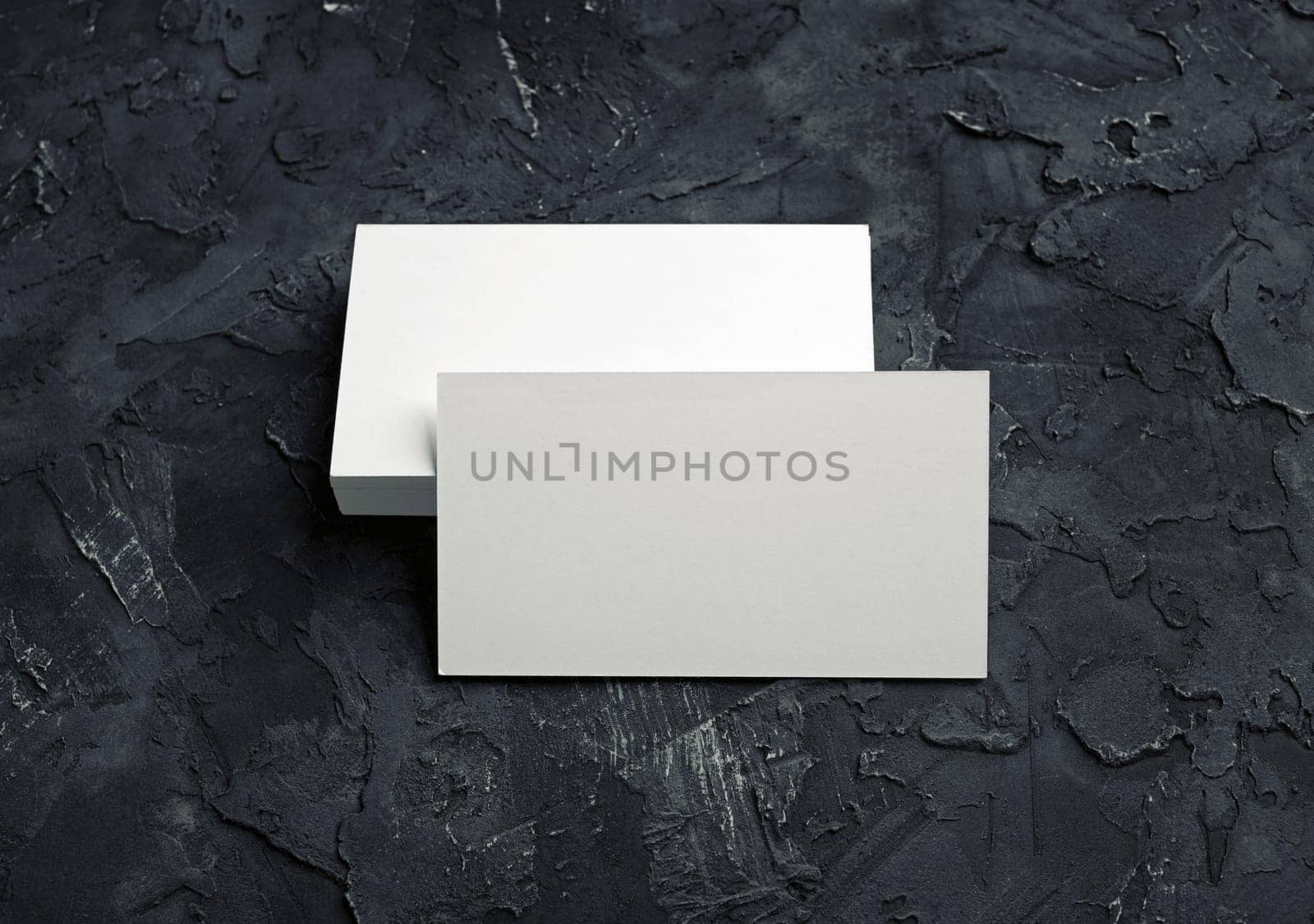 Photo of blank business cards on black plaster background. Mock-up for branding identity for designers.