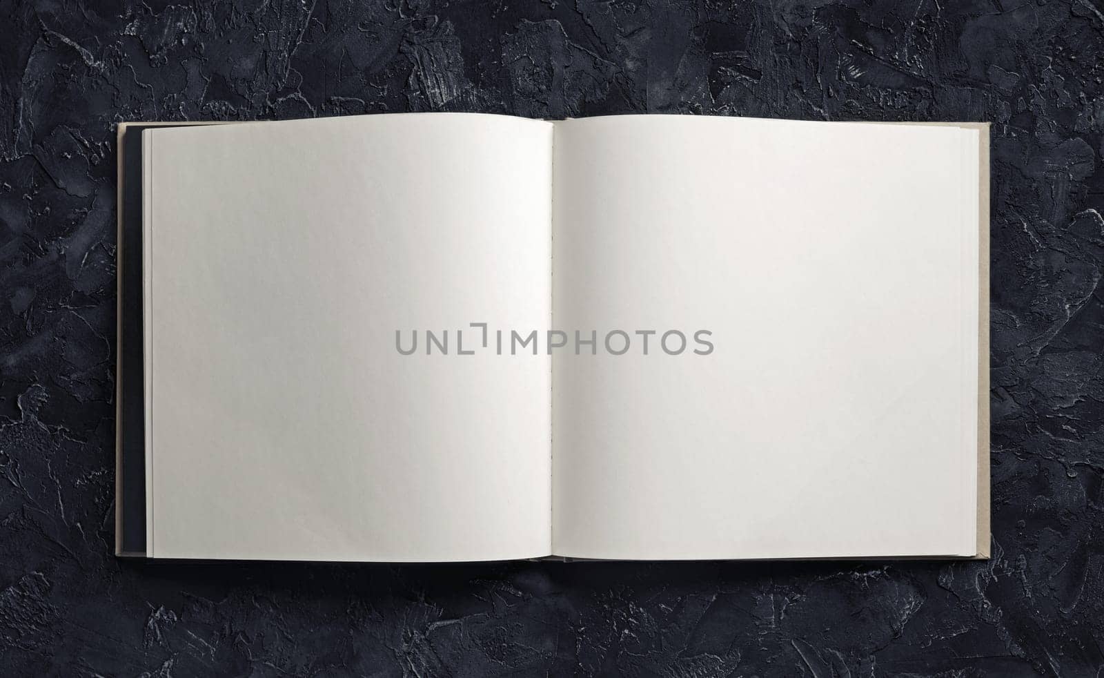 Blank open book or brochure on black plaster background. Mock-up for graphic designers portfolios. Responsive design mockup.