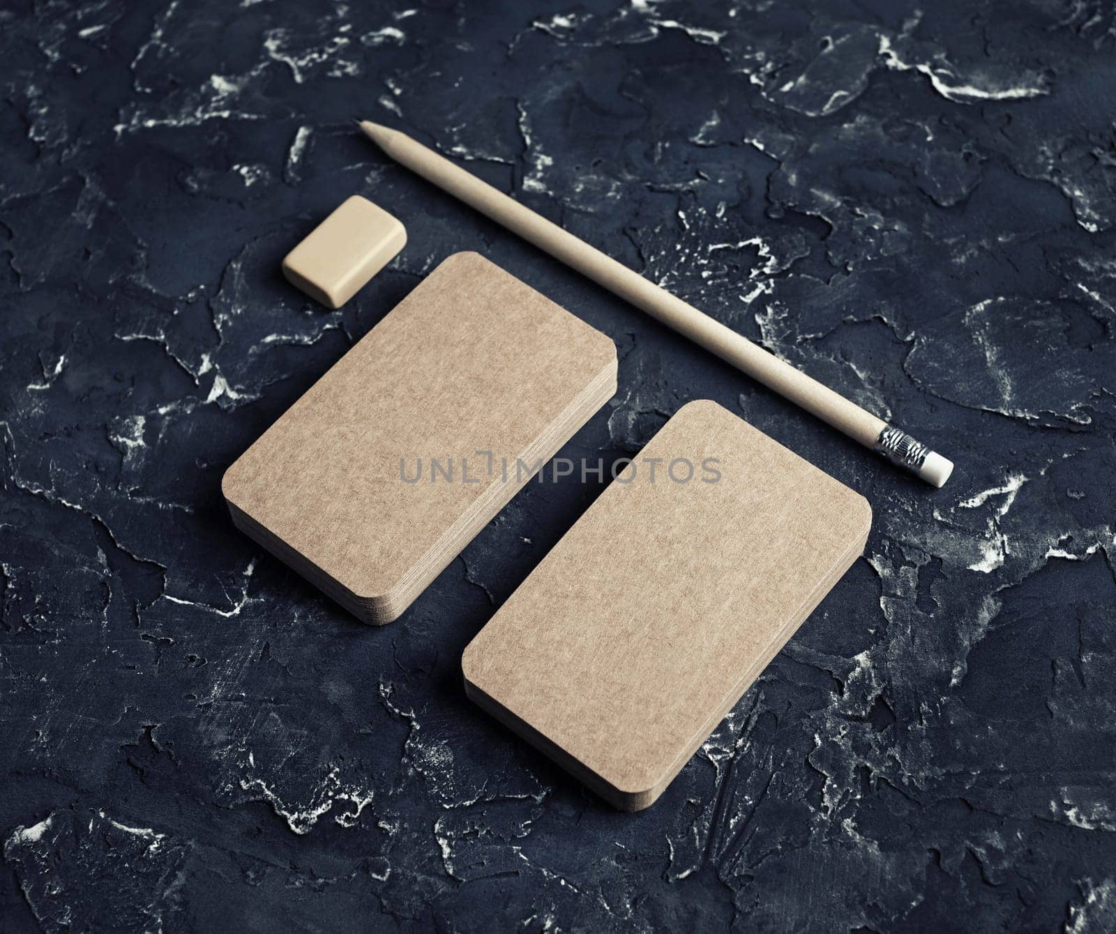Blank kraft business cards, pencil and eraser on black plaster background. Blank stationery set.