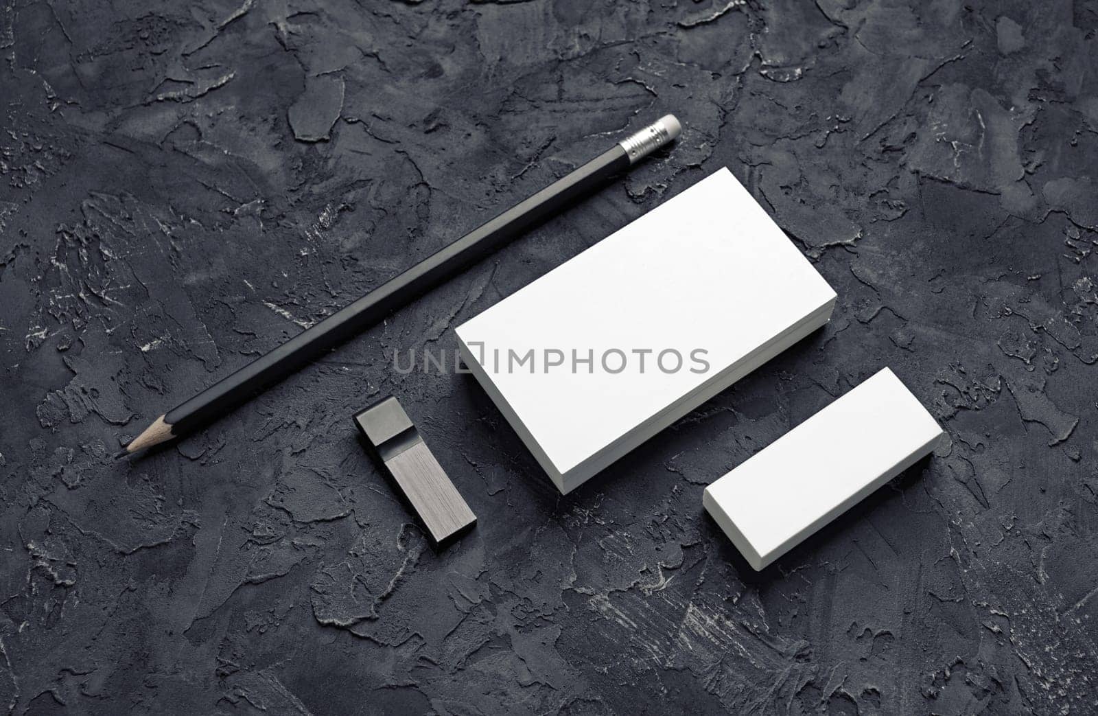 Brand identity mockup. Blank business card, pencil, eraser and usb flash drive on black plaster background.