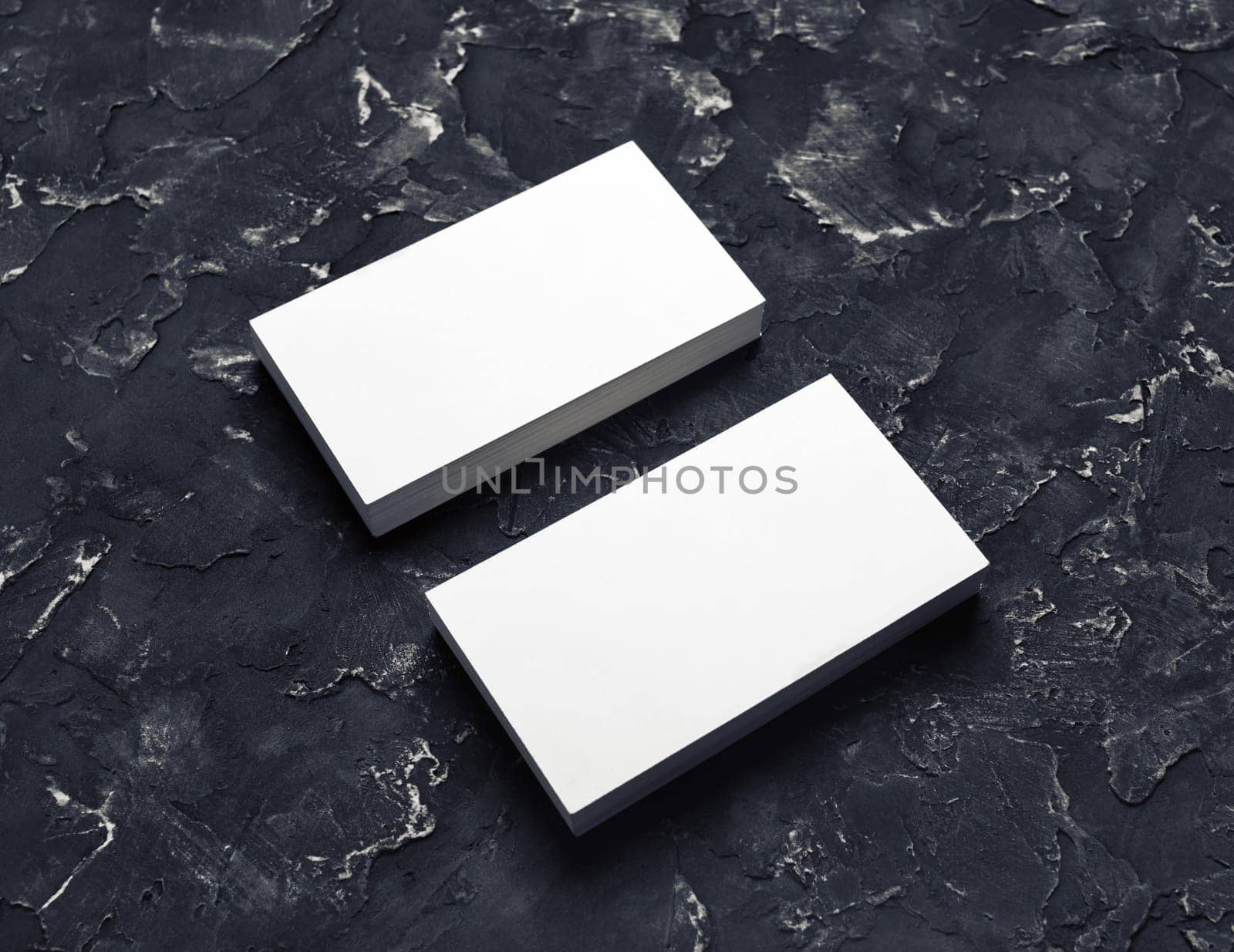 Photo of blank business cards on black plaster background. Mock-up for branding identity for designers.