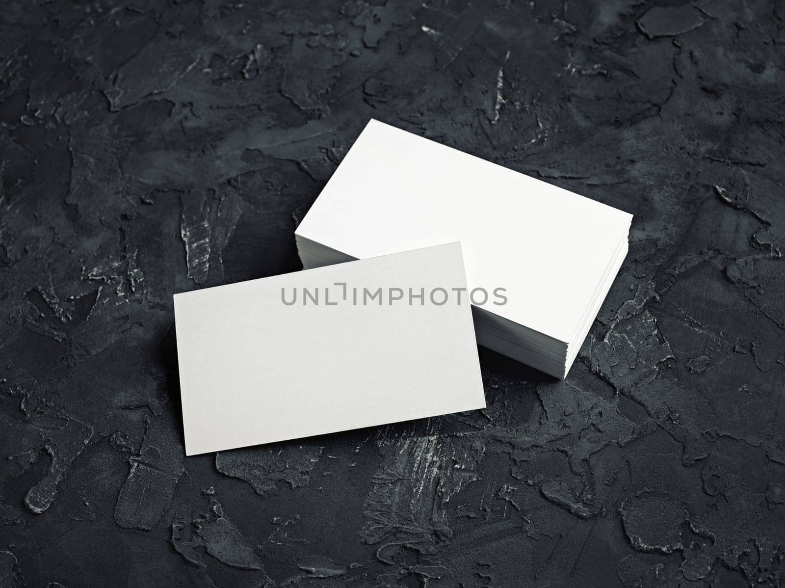 Photo of blank business cards on black plaster background. Template for your design.