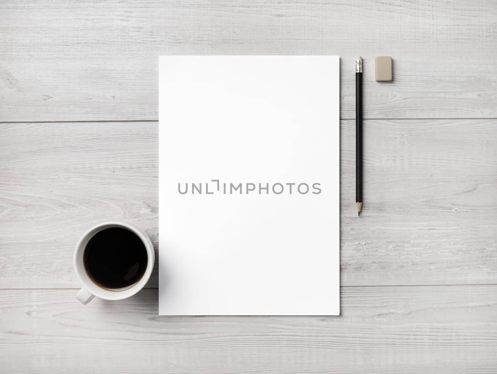 Blank white letterhead, coffee cup, pen and eraser on light wooden background.