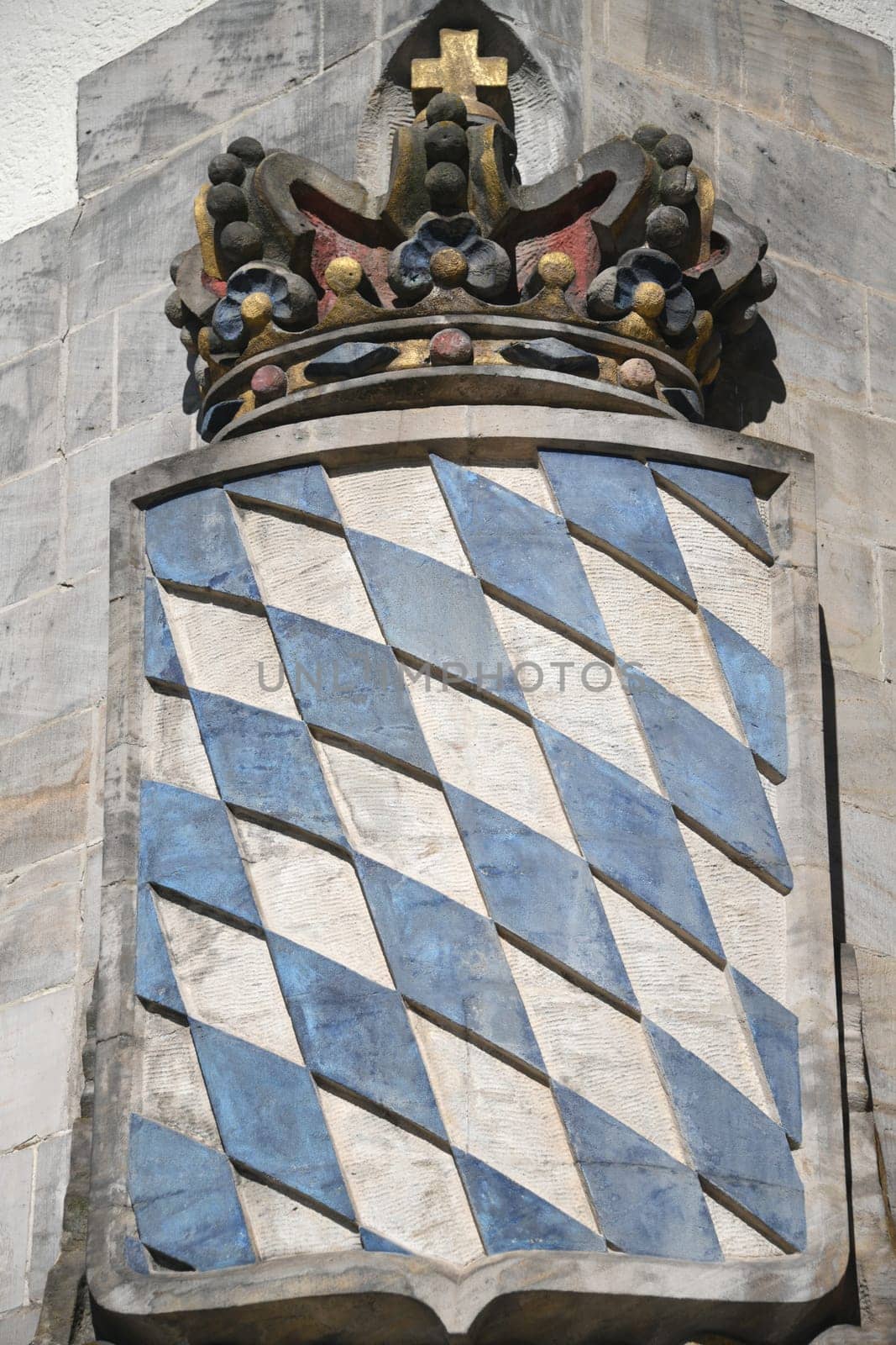 The Bavarian coat of arms with its blue and white rhombuses and crown in the Free State of Bavaria on a wall.