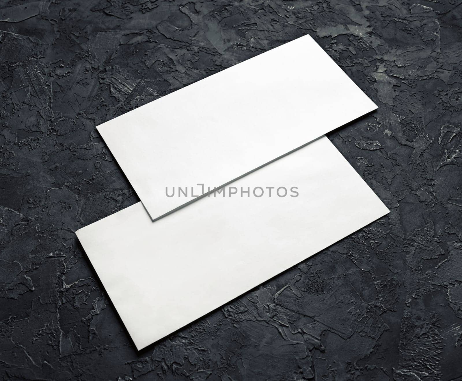 Two blank envelopes on black plaster background. Template for branding identity.