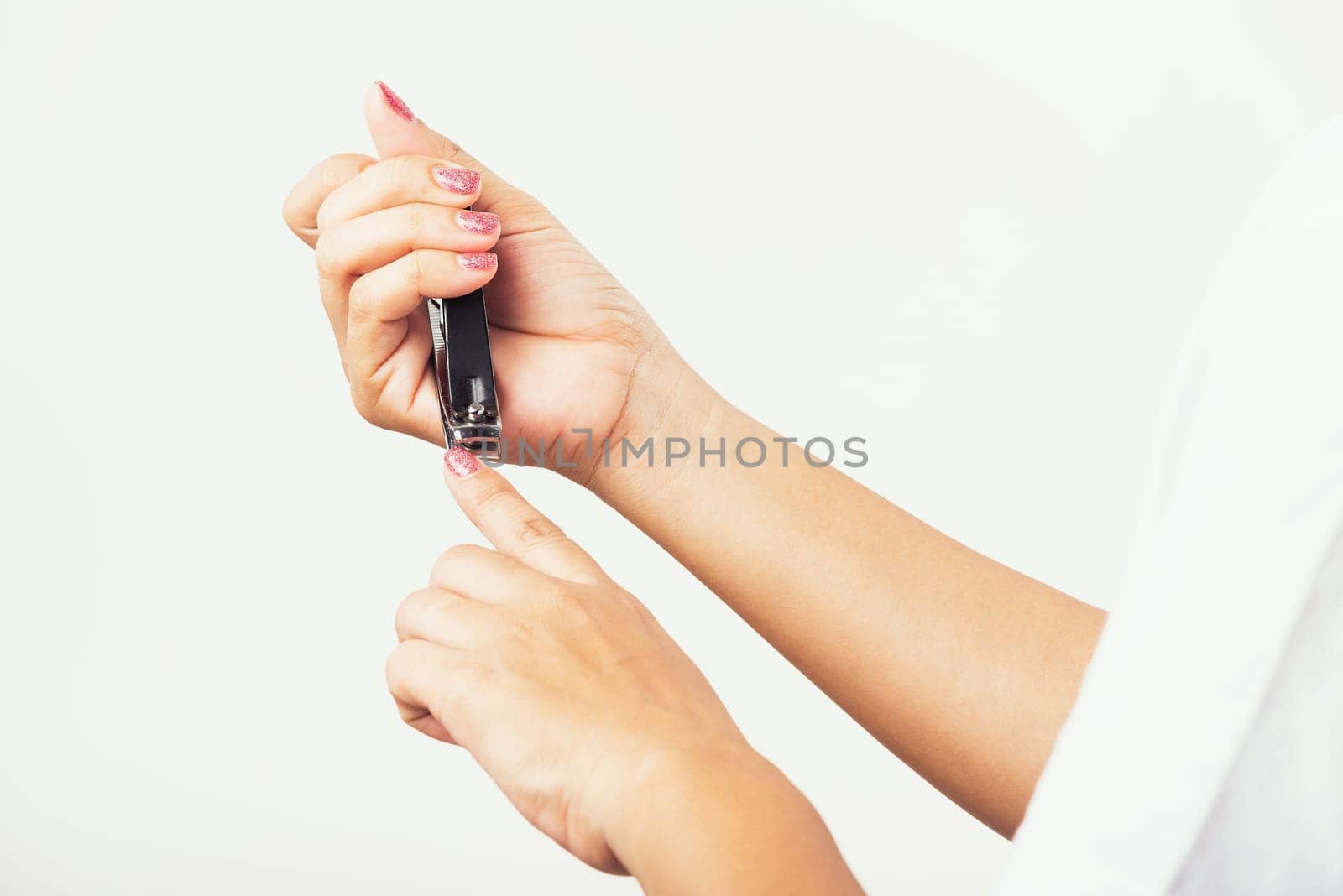 Close up young Asian woman have tool cutting nails fingernails on finger using a nail clipper. Female using tweezers by herself, studio shot isolated on white background, Healthcare concept