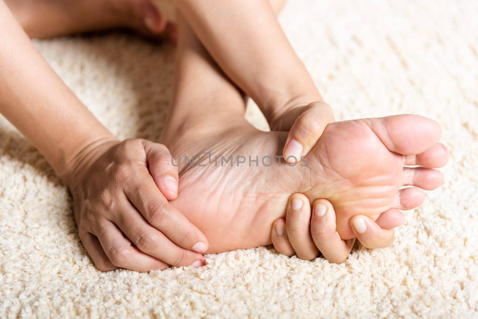 Foot pain, Asian woman feeling pain in her foot at home, female suffering from feet ache use hand massage relax muscle from soles in home interior, Healthcare problems and podiatry medical concept