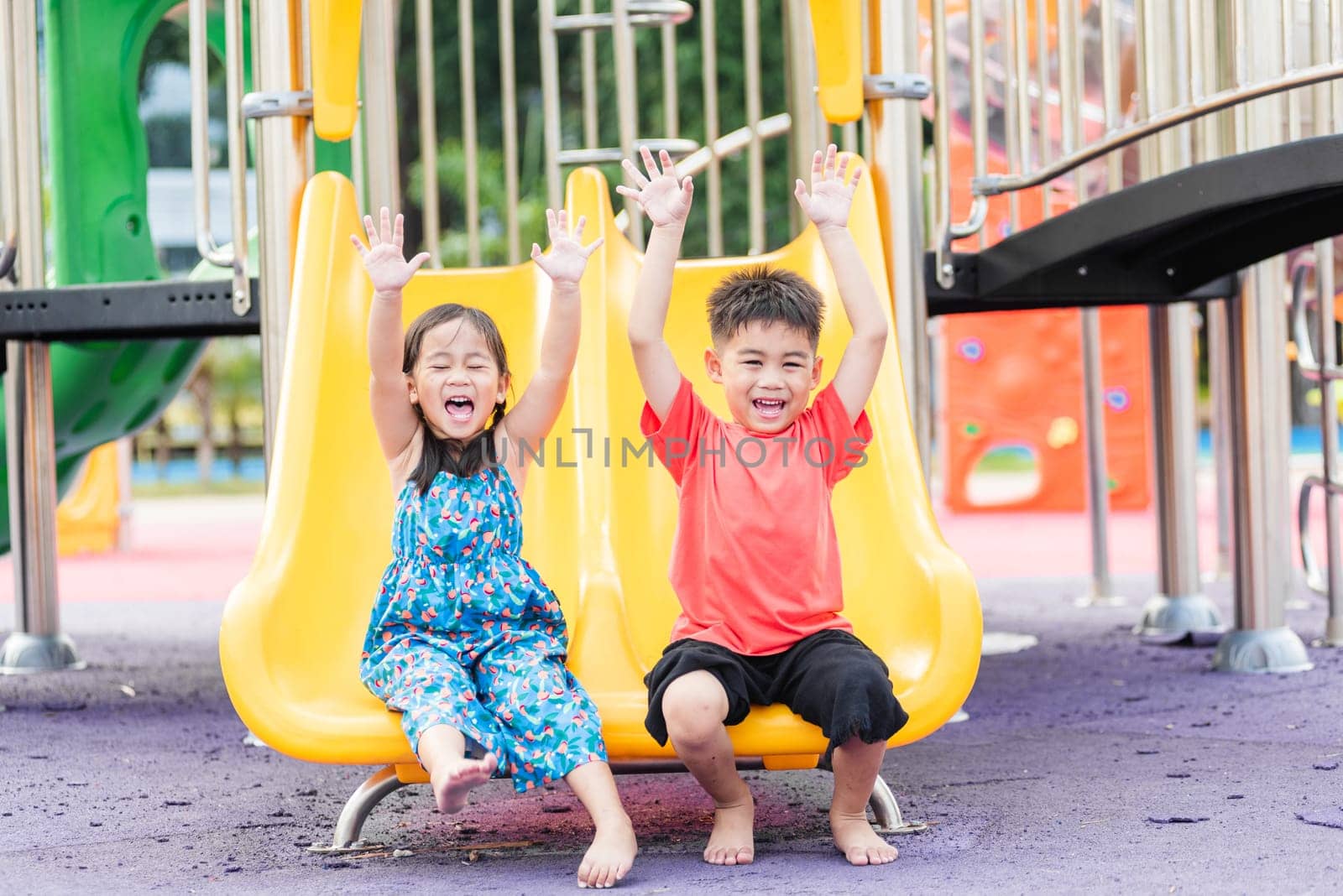 Asian child smiling playing on slider bar toy outdoor playground, happy preschool little kid having funny while playing on the playground equipment in the daytime in summer, Little girl & boy climbing
