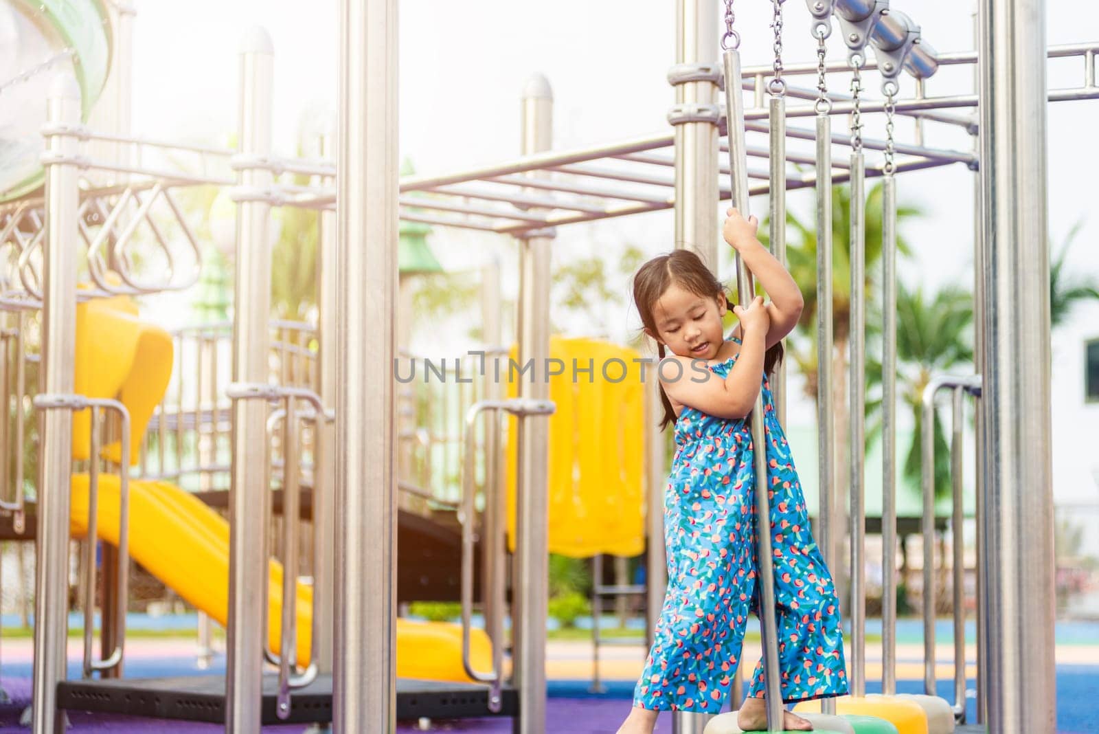Asian child playing on outdoor playground, happy preschool little kid having funny while playing on the playground equipment in the daytime in summer, Outside education, Little girl climbing