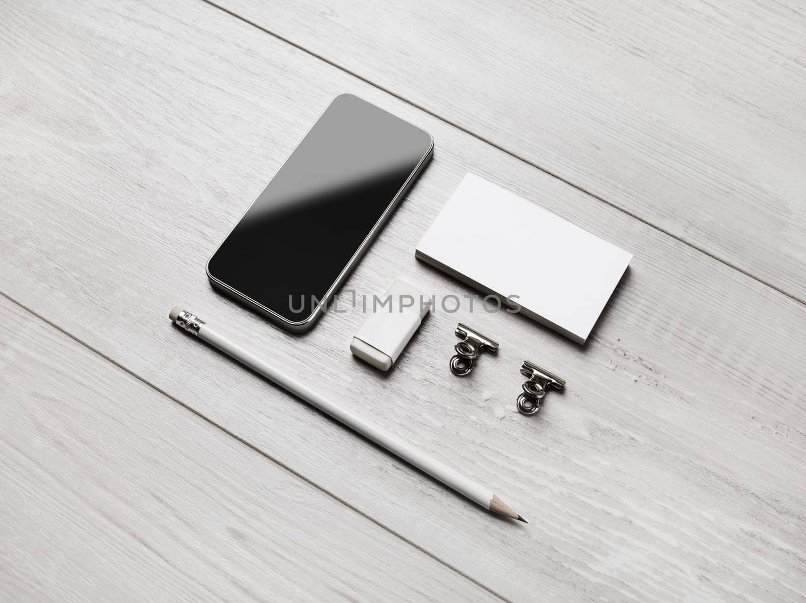 Branding stationery template. Blank business cards, smartphone, pencil, eraser and clips on light wooden background. ID mockup.