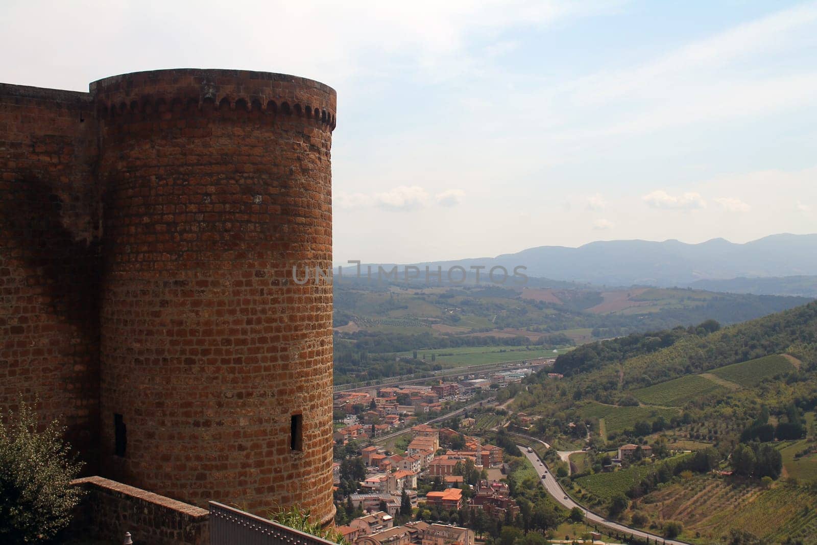 Stone tower and green hills with rooftops near Orvieto in the center of Italy