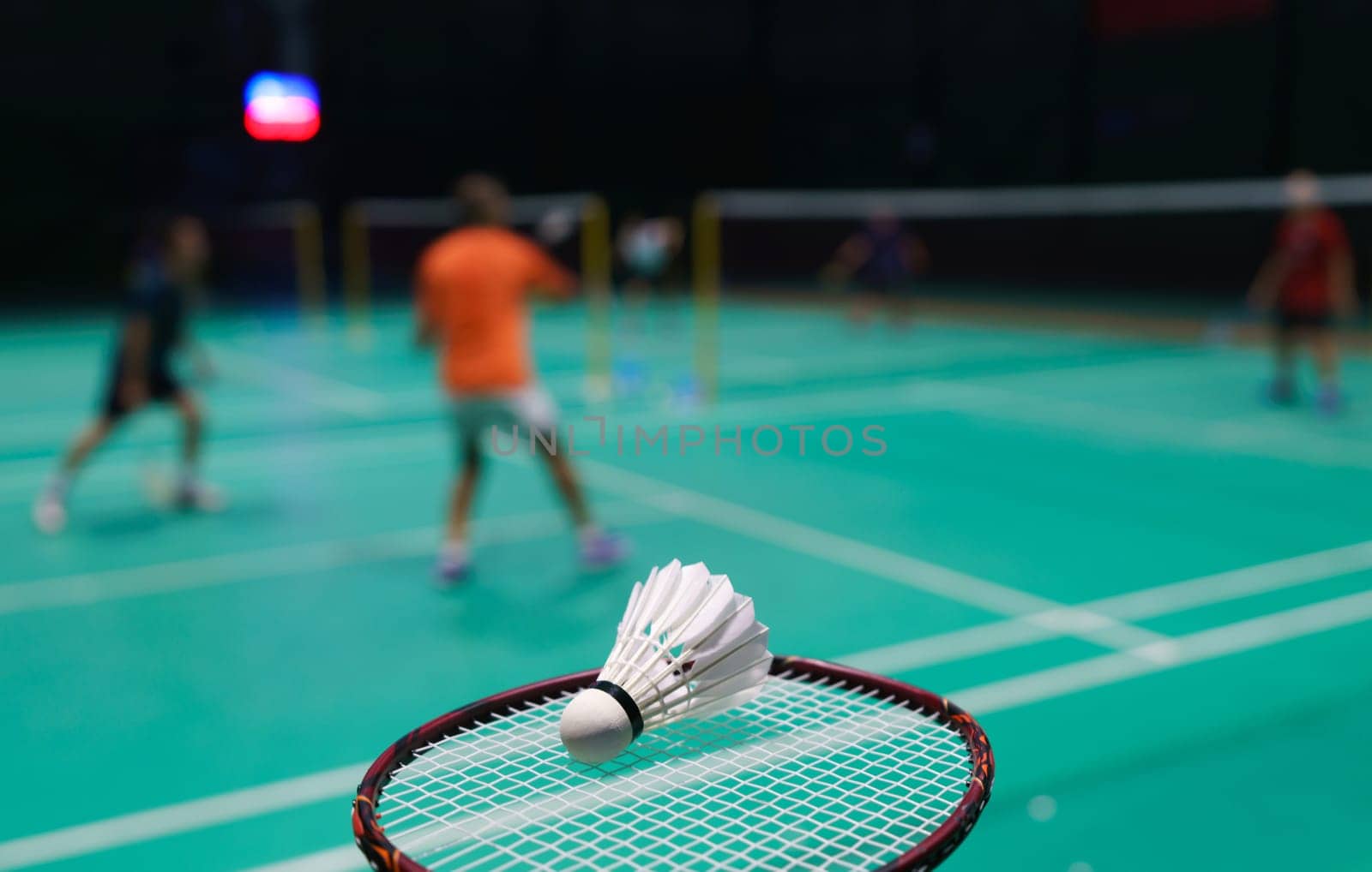 shuttlecock on green badminton playing court with player in background